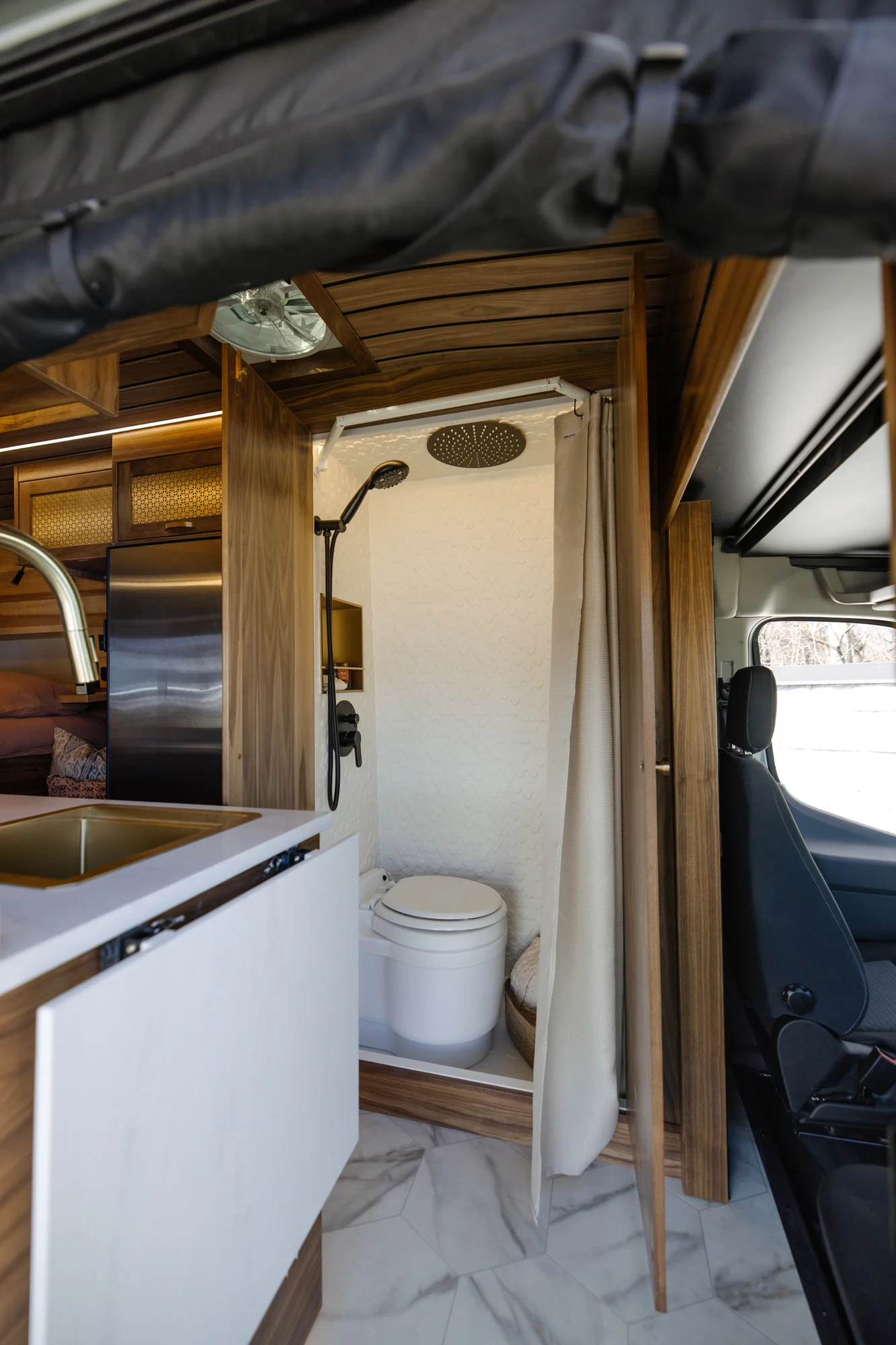 The Drifter 101 custom Ford Transit campervan built for Peter by Drifter Vans, with rich walnut cabinetry, brass mesh panels, and a tiled wet bath