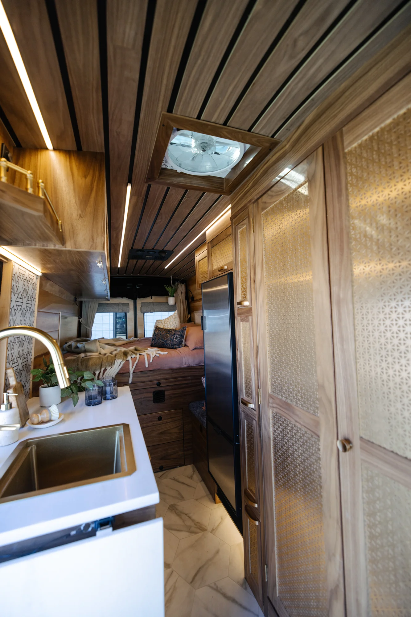 The Drifter 101 custom Ford Transit campervan built for Peter by Drifter Vans, with rich walnut cabinetry, brass mesh panels, and a tiled wet bath