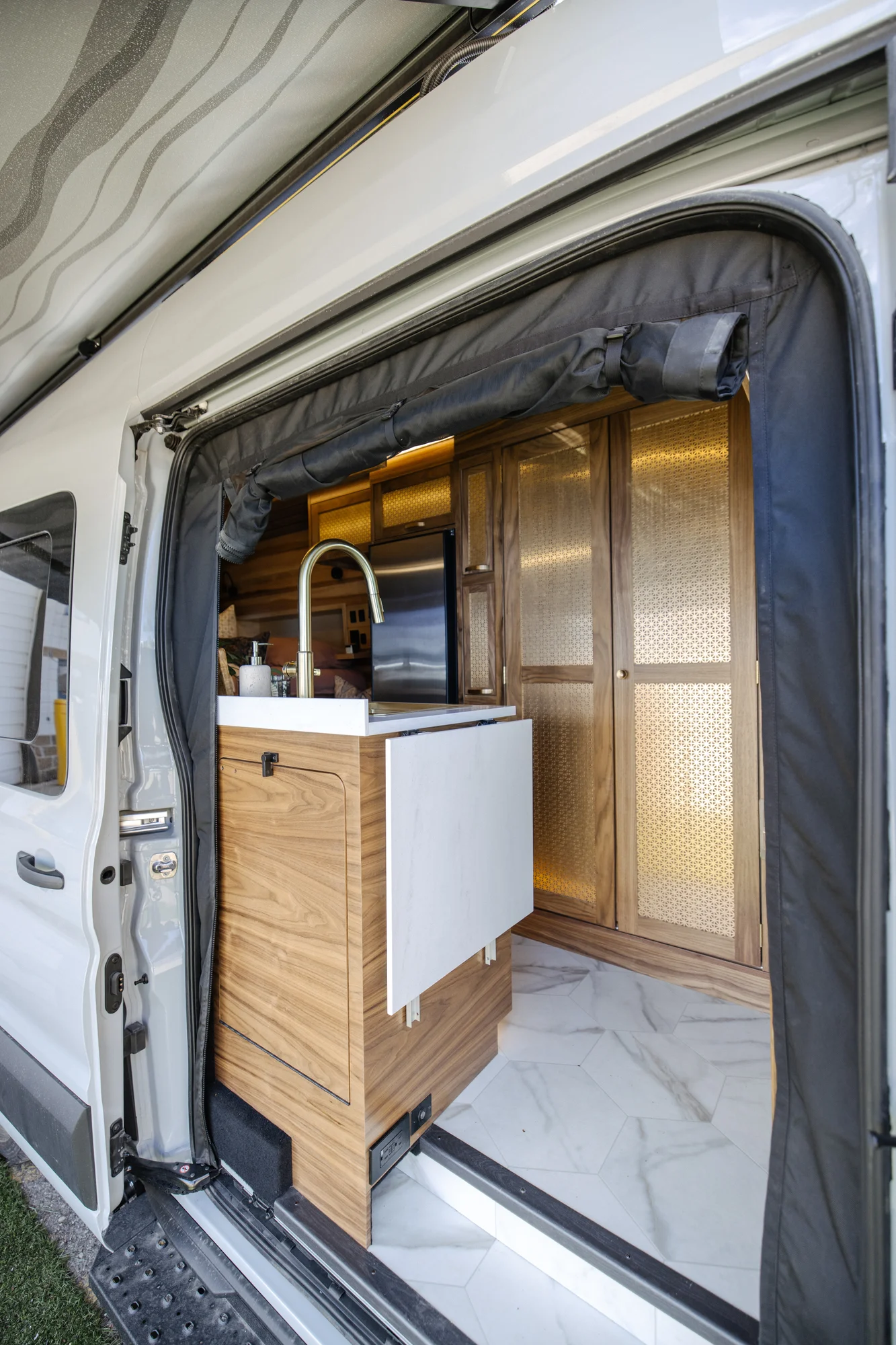 The Drifter 101 custom Ford Transit campervan built for Peter by Drifter Vans, with rich walnut cabinetry, brass mesh panels, and a tiled wet bath
