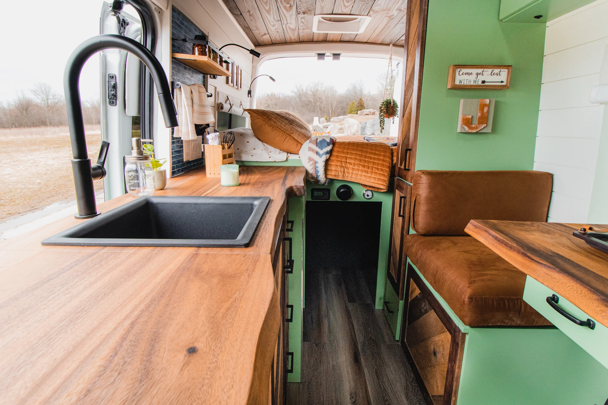 The Drifter 101 custom Ford Transit campervan built for Josh by Drifter Vans, Wanderer layout with forest green cabinetry, dark wood countertop, and leather booth seating