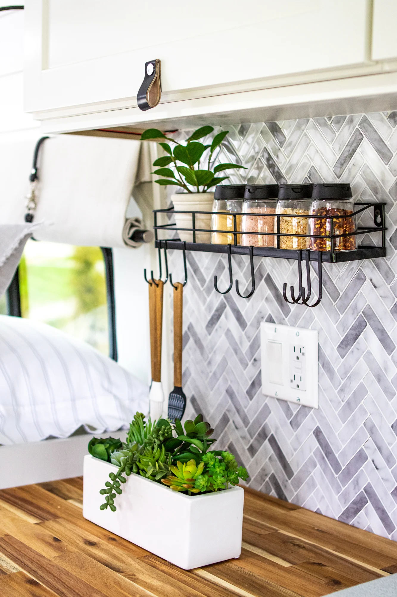 The Drifter 101 custom Ram ProMaster campervan built for Halley by Drifter Vans, Wanderer layout with a herringbone tile backsplash, butcher block countertop, and white cabinetry