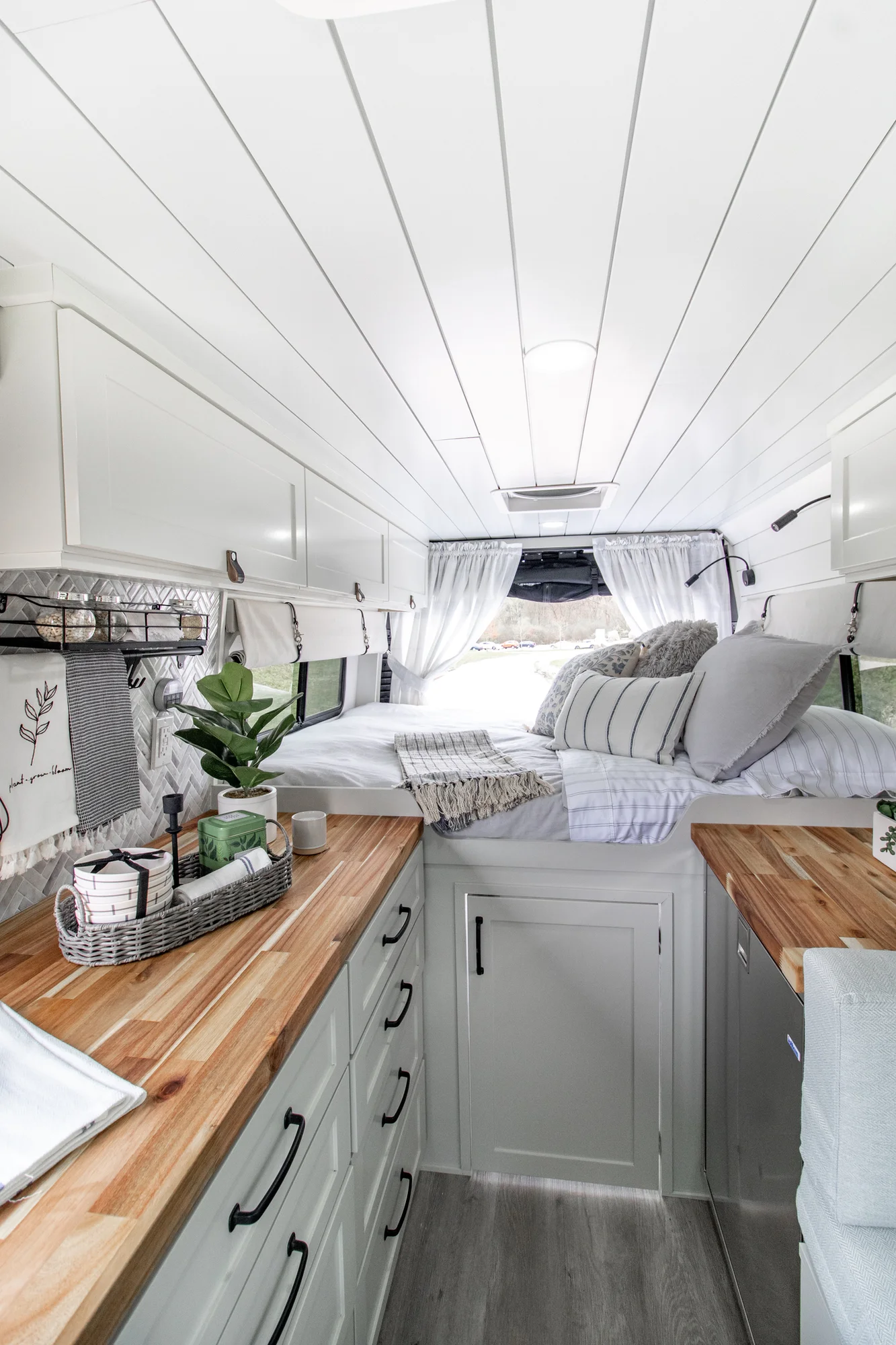 The Drifter 101 custom Ram ProMaster campervan built for Halley by Drifter Vans, Wanderer layout with a herringbone tile backsplash, butcher block countertop, and white cabinetry