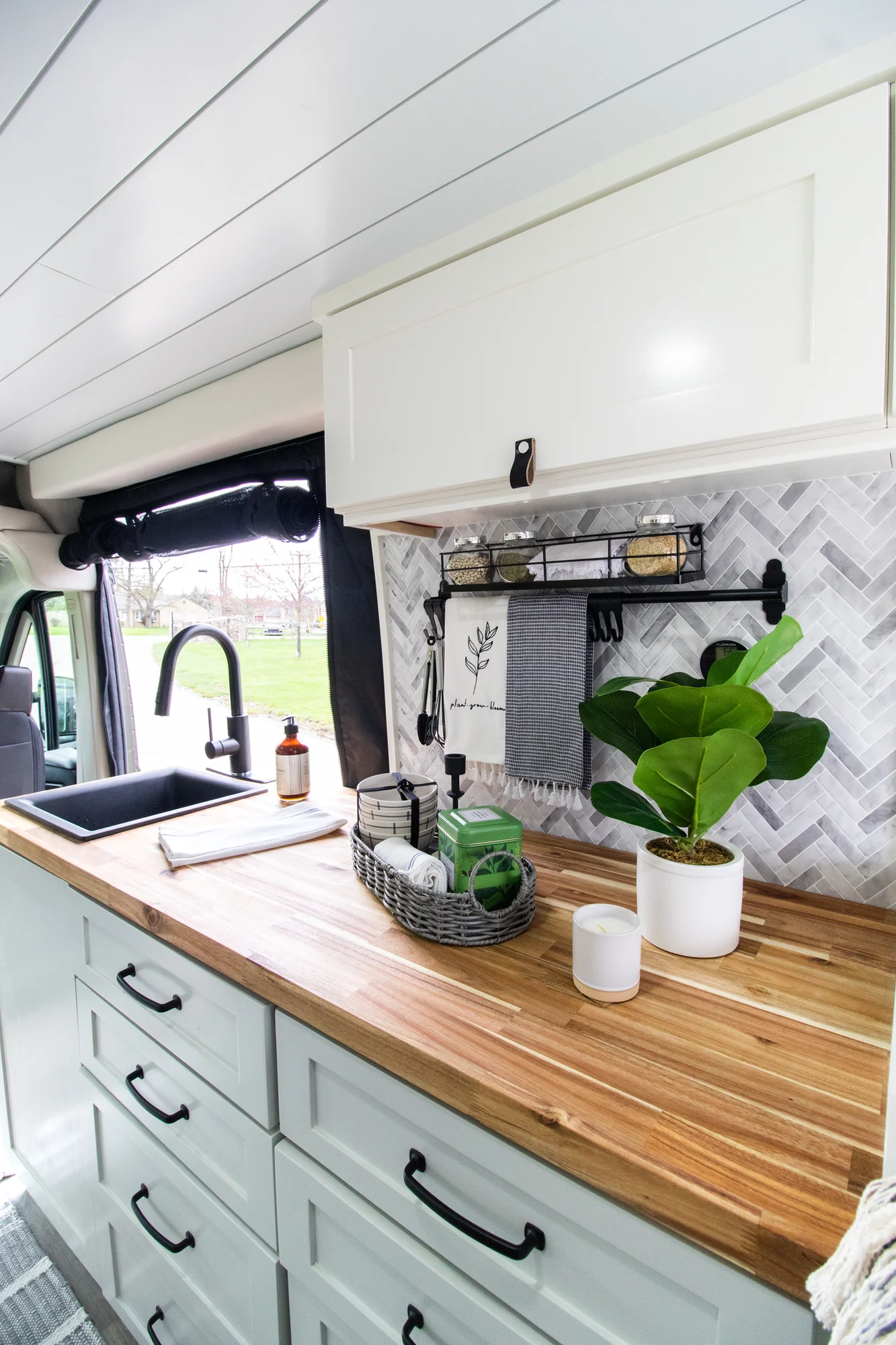 The Drifter 101 custom Ram ProMaster campervan built for Halley by Drifter Vans, Wanderer layout with a herringbone tile backsplash, butcher block countertop, and white cabinetry