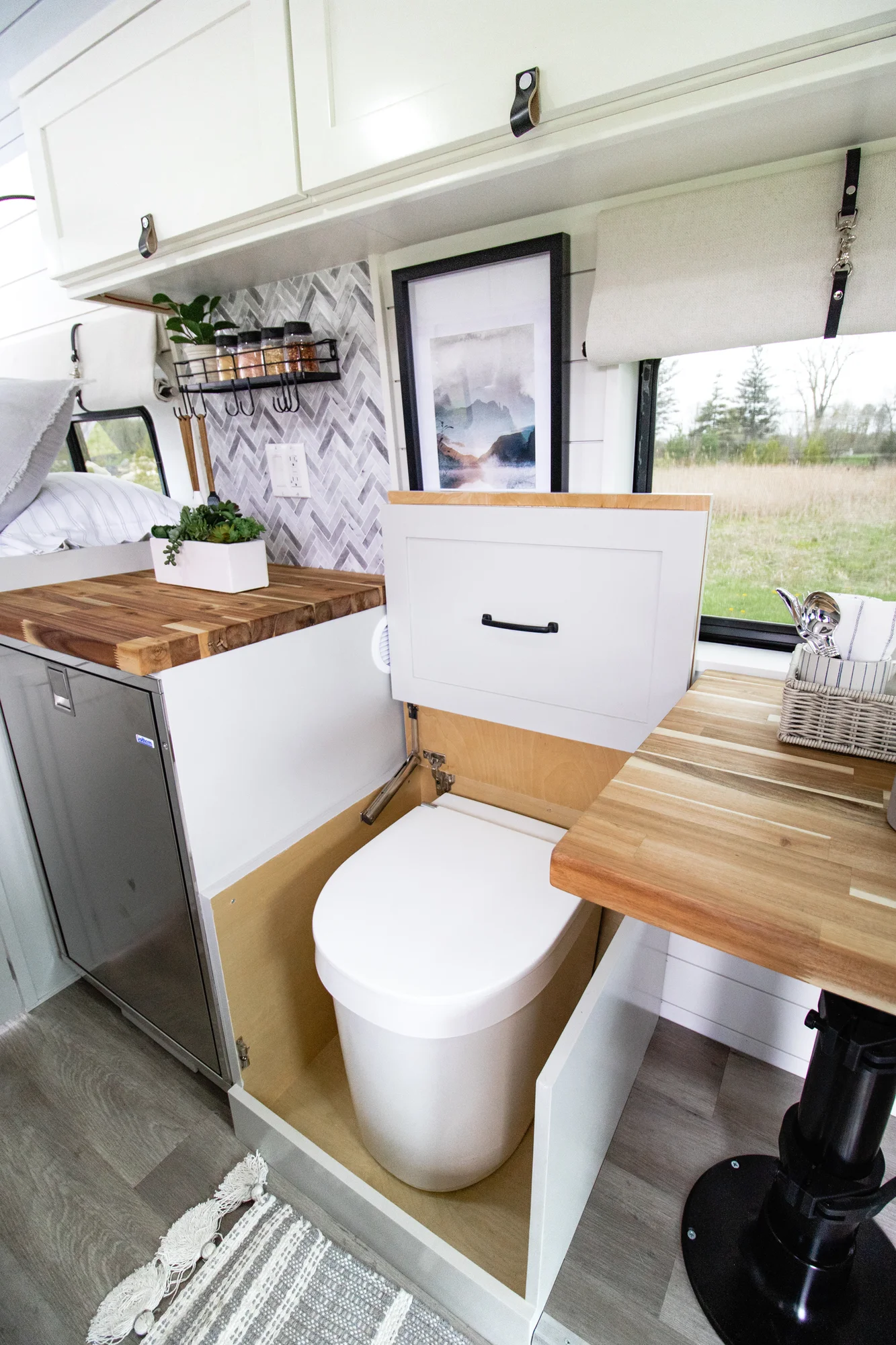 The Drifter 101 custom Ram ProMaster campervan built for Halley by Drifter Vans, Wanderer layout with a herringbone tile backsplash, butcher block countertop, and white cabinetry