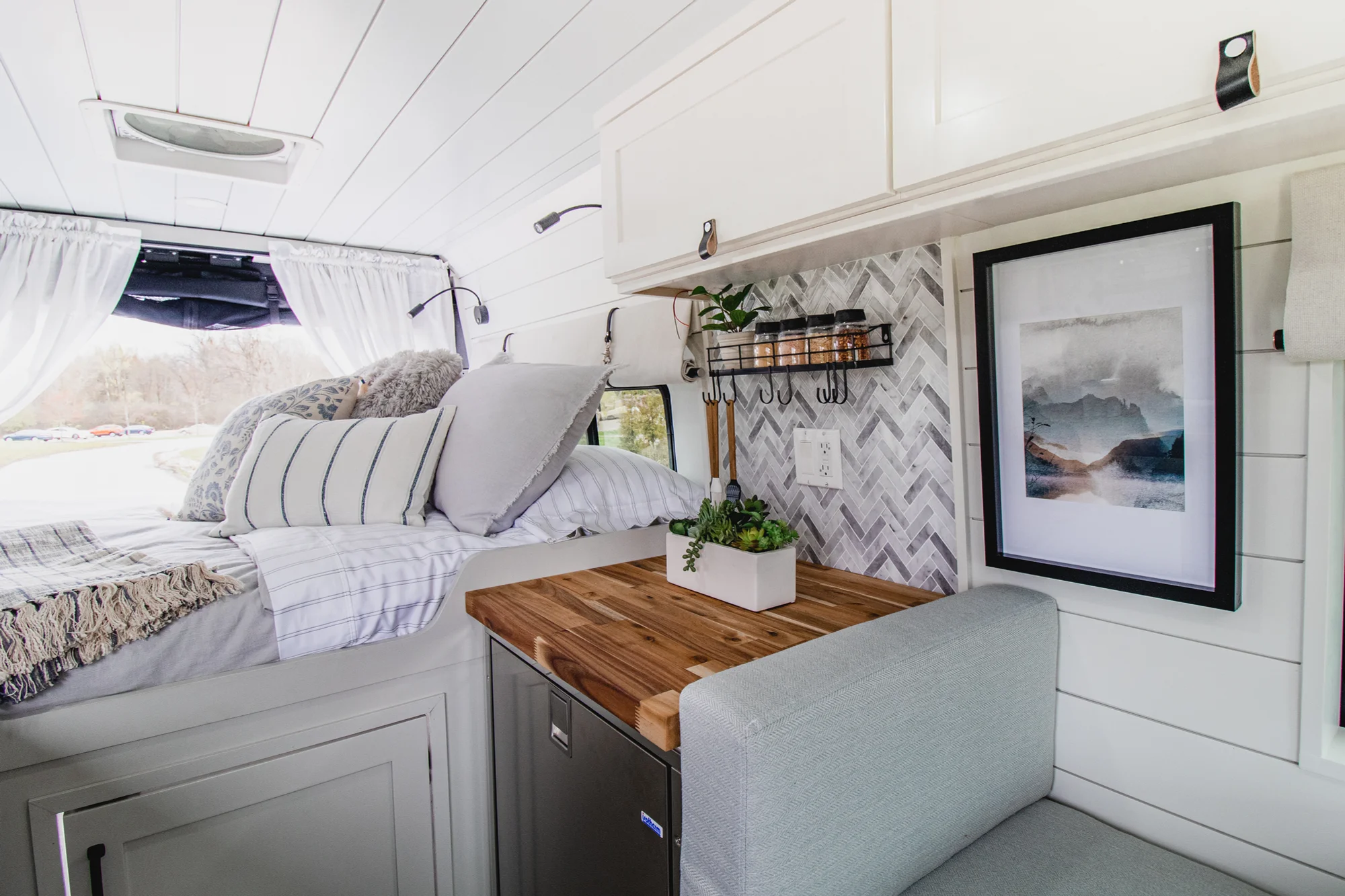 The Drifter 101 custom Ram ProMaster campervan built for Halley by Drifter Vans, Wanderer layout with a herringbone tile backsplash, butcher block countertop, and white cabinetry