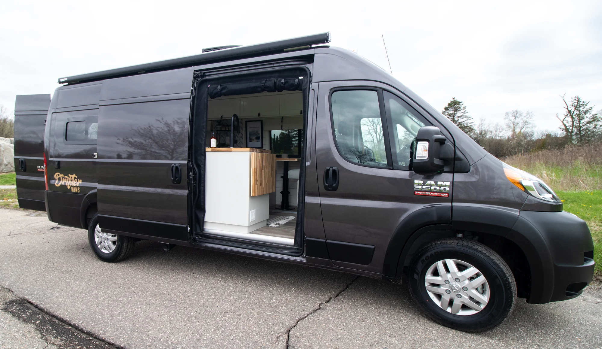 The Drifter 101 custom Ram ProMaster campervan built for Halley by Drifter Vans, Wanderer layout with a herringbone tile backsplash, butcher block countertop, and white cabinetry