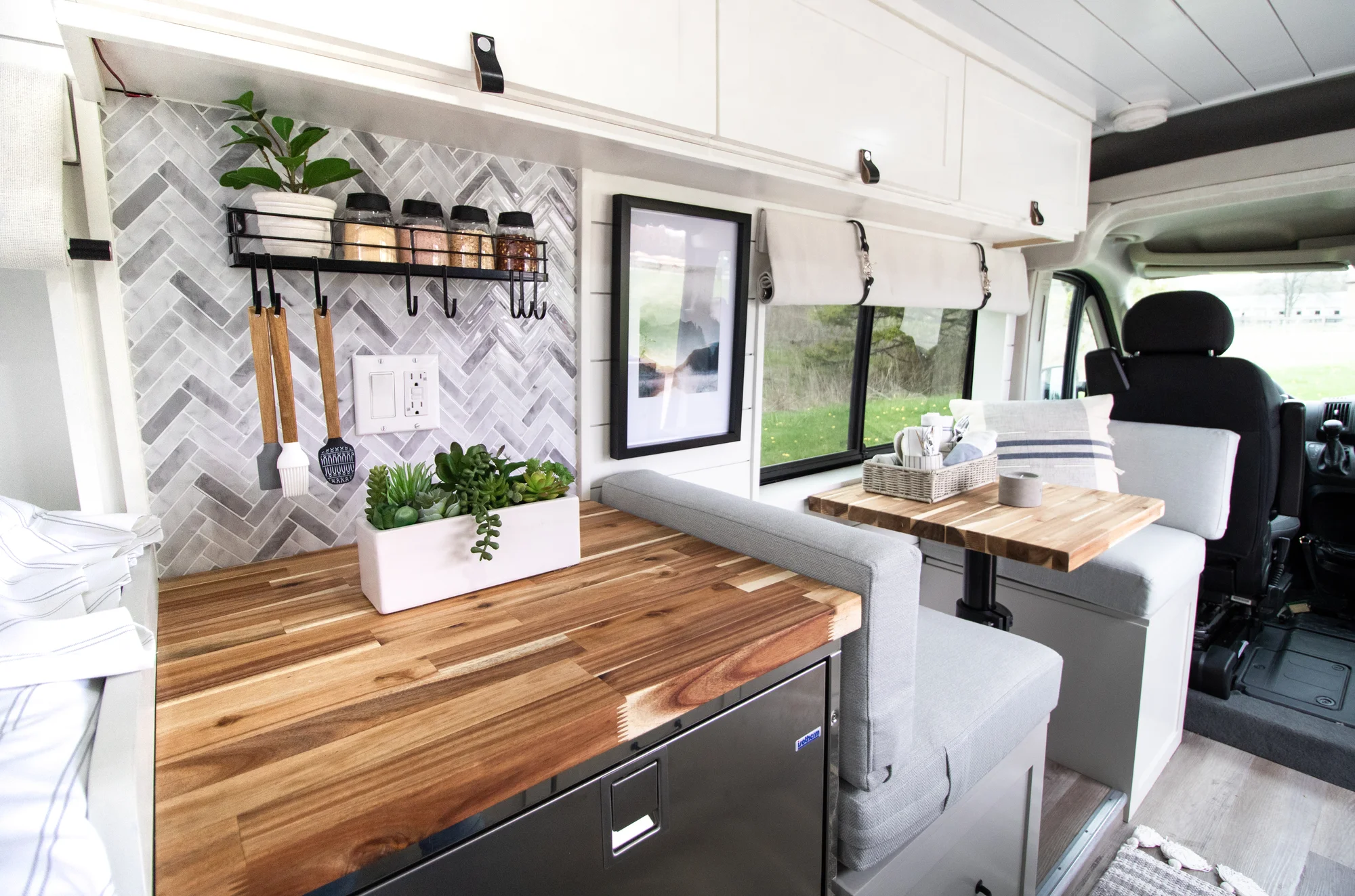 The Drifter 101 custom Ram ProMaster campervan built for Halley by Drifter Vans, Wanderer layout with a herringbone tile backsplash, butcher block countertop, and white cabinetry