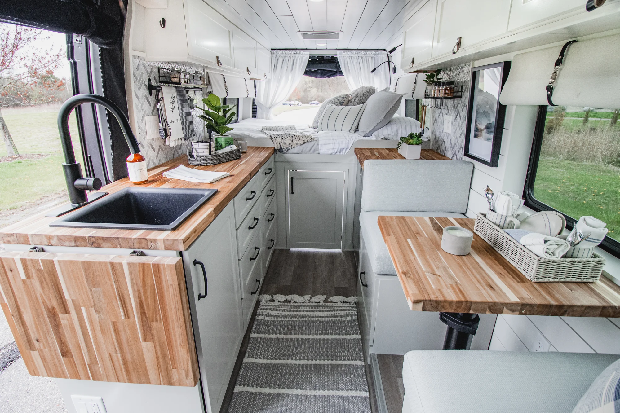 The Drifter 101 custom Ram ProMaster campervan built for Halley by Drifter Vans, Wanderer layout with a herringbone tile backsplash, butcher block countertop, and white cabinetry