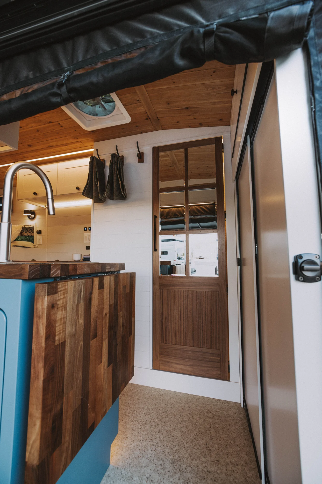 The Drifter 101 custom Ford Transit campervan built for Charlie and Linda by Drifter Vans, Nomadik layout with a Vermont slate shower, sky-blue cabinetry, and butcher block countertop