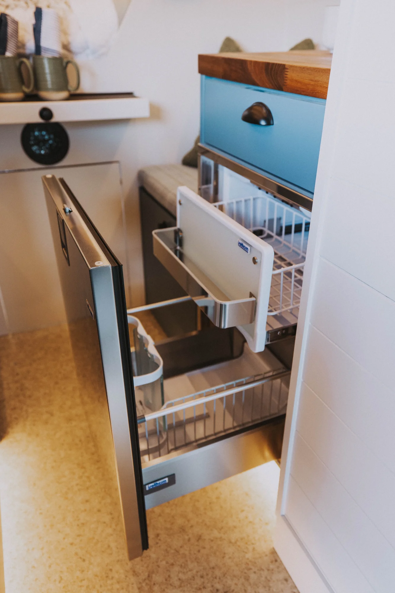 The Drifter 101 custom Ford Transit campervan built for Charlie and Linda by Drifter Vans, Nomadik layout with a Vermont slate shower, sky-blue cabinetry, and butcher block countertop