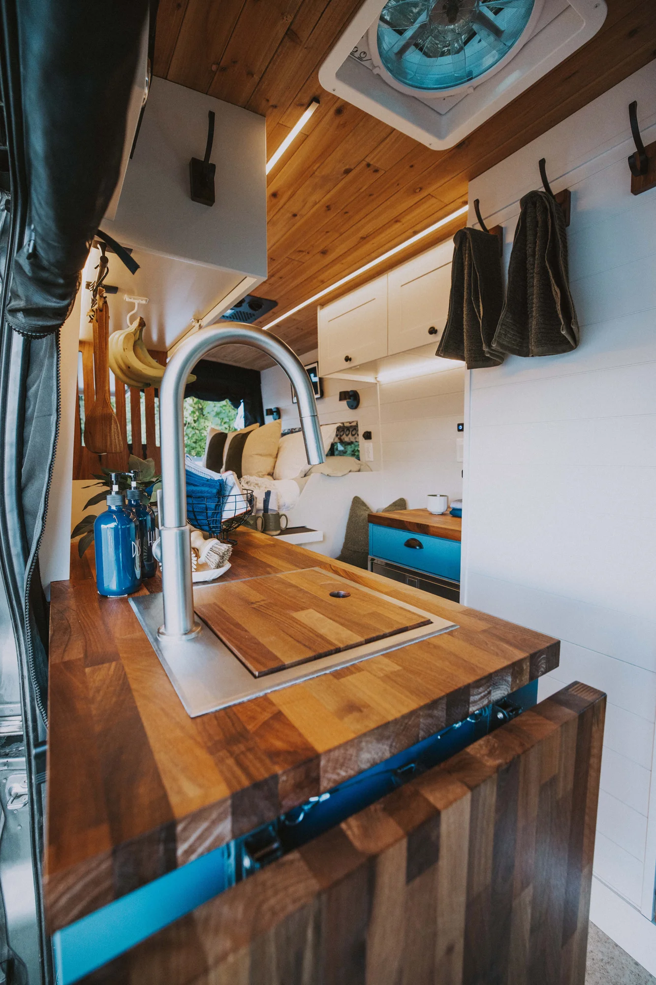 The Drifter 101 custom Ford Transit campervan built for Charlie and Linda by Drifter Vans, Nomadik layout with a Vermont slate shower, sky-blue cabinetry, and butcher block countertop