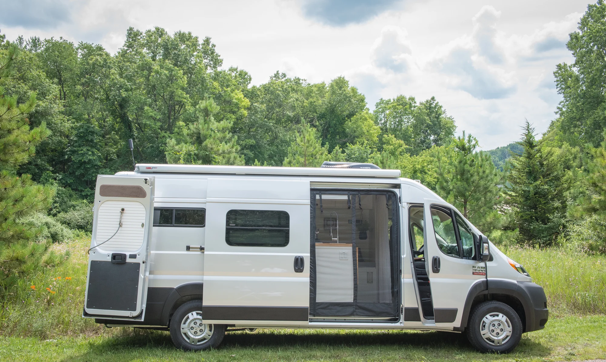 The Drifter 101 custom Ram ProMaster campervan built for Marcia by Drifter Vans, with white shiplap walls, wood countertop, an enclosed shower, and a remote work setup