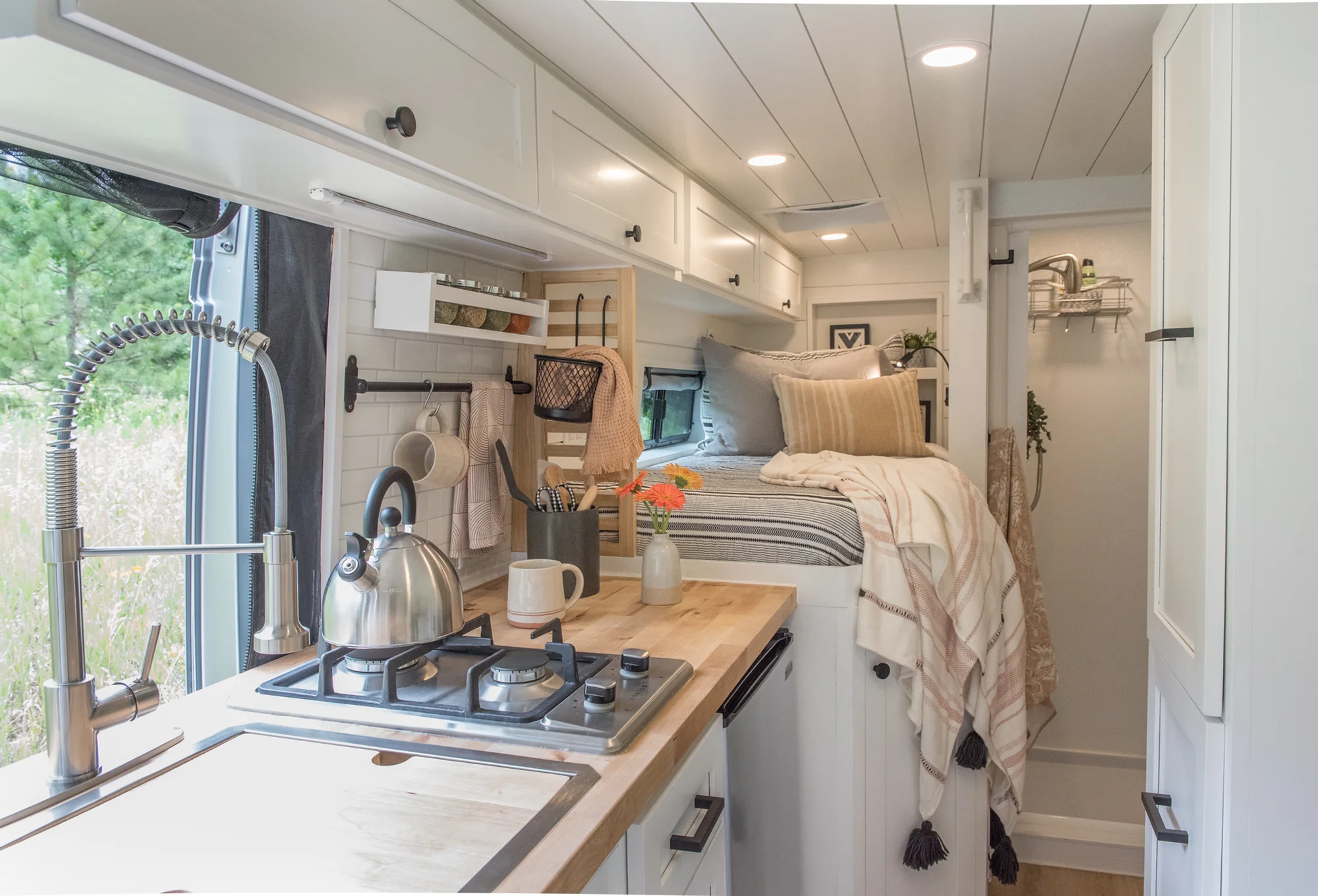 The Drifter 101 custom Ram ProMaster campervan built for Marcia by Drifter Vans, with white shiplap walls, wood countertop, an enclosed shower, and a remote work setup