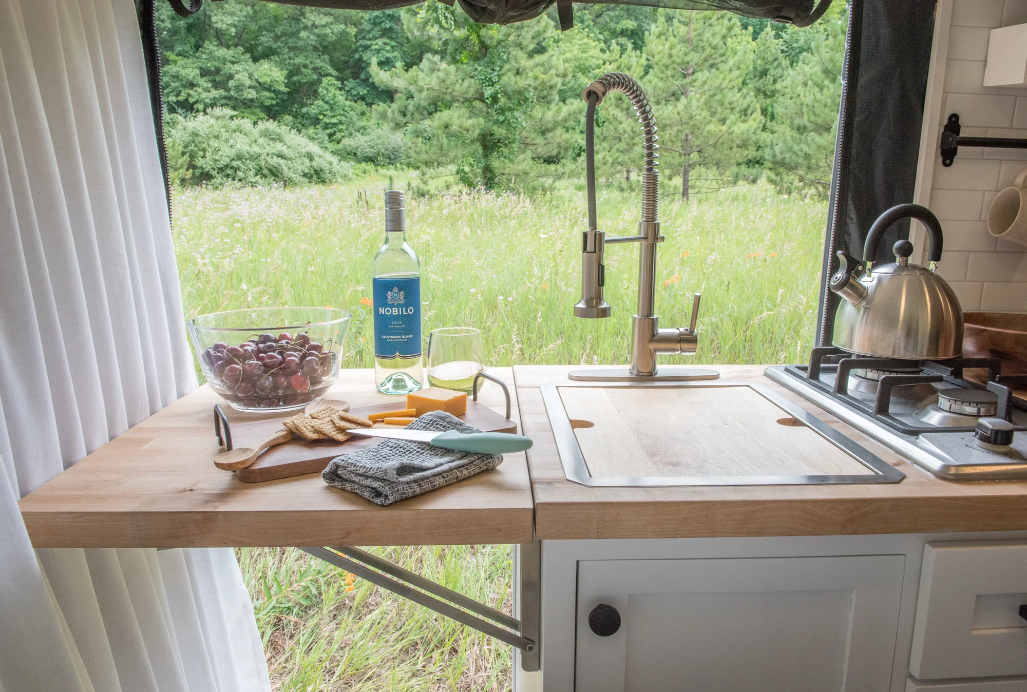 The Drifter 101 custom Ram ProMaster campervan built for Marcia by Drifter Vans, with white shiplap walls, wood countertop, an enclosed shower, and a remote work setup