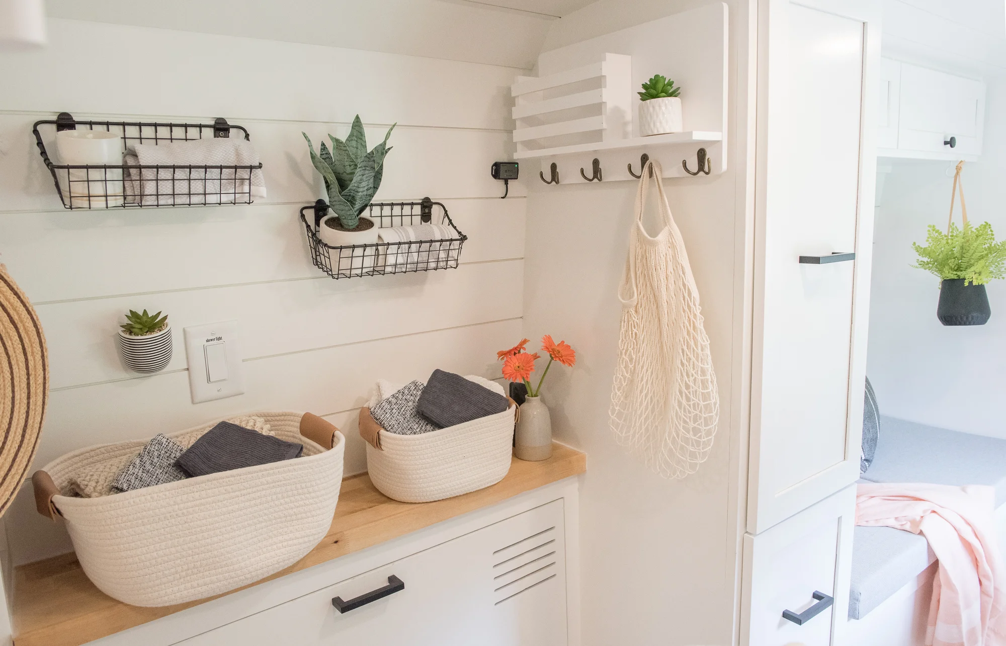 The Drifter 101 custom Ram ProMaster campervan built for Marcia by Drifter Vans, with white shiplap walls, wood countertop, an enclosed shower, and a remote work setup