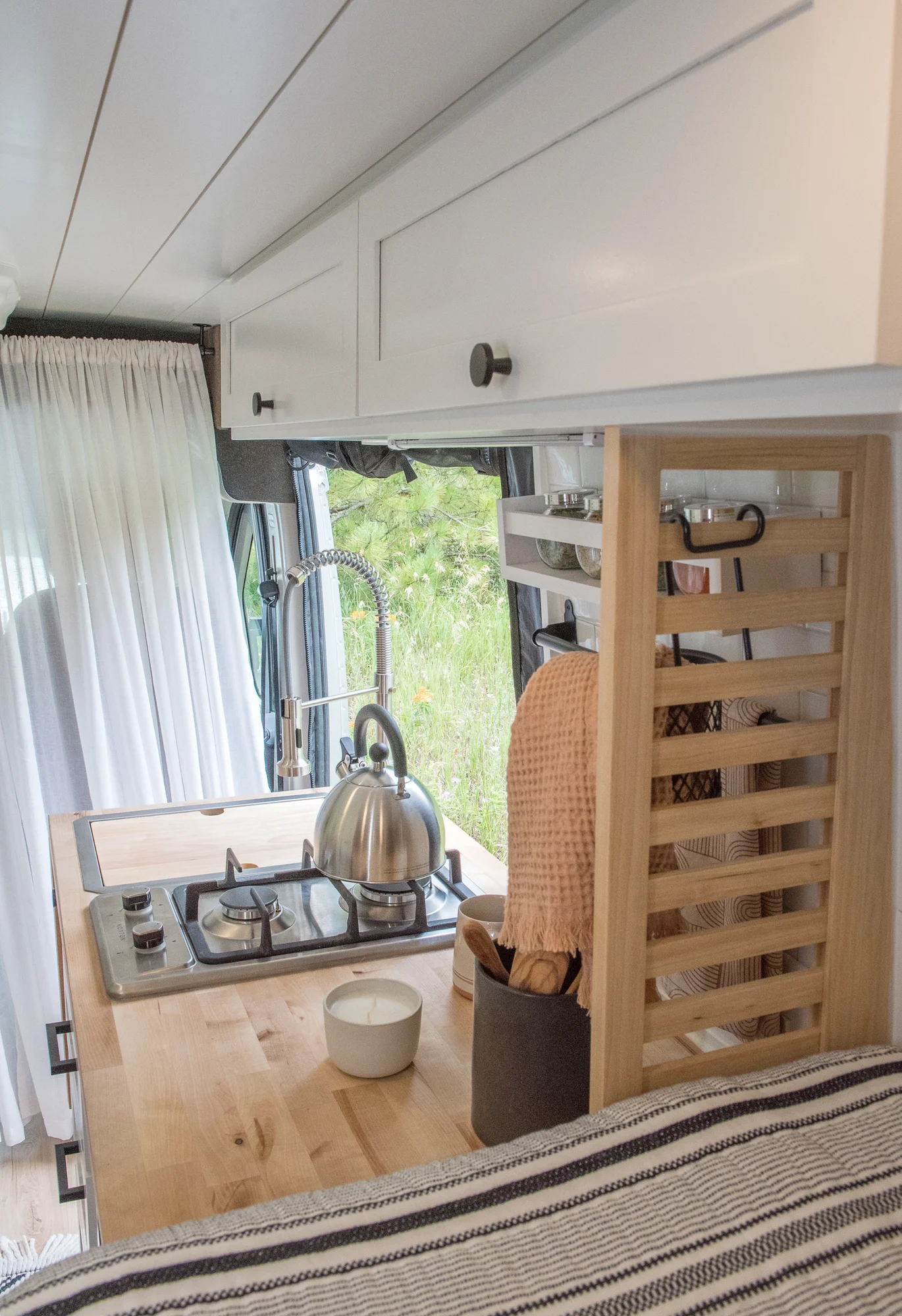 The Drifter 101 custom Ram ProMaster campervan built for Marcia by Drifter Vans, with white shiplap walls, wood countertop, an enclosed shower, and a remote work setup