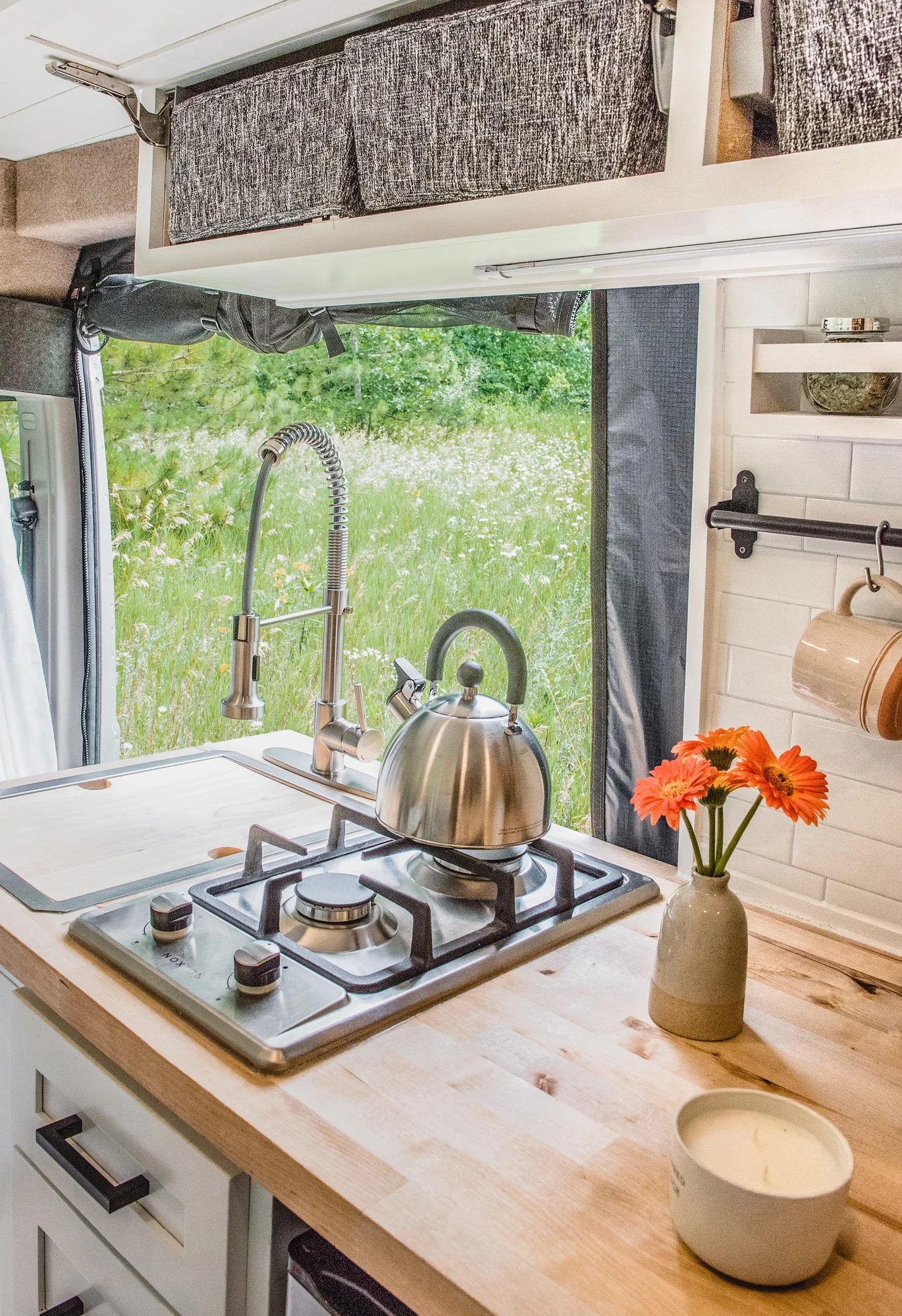 The Drifter 101 custom Ram ProMaster campervan built for Marcia by Drifter Vans, with white shiplap walls, wood countertop, an enclosed shower, and a remote work setup