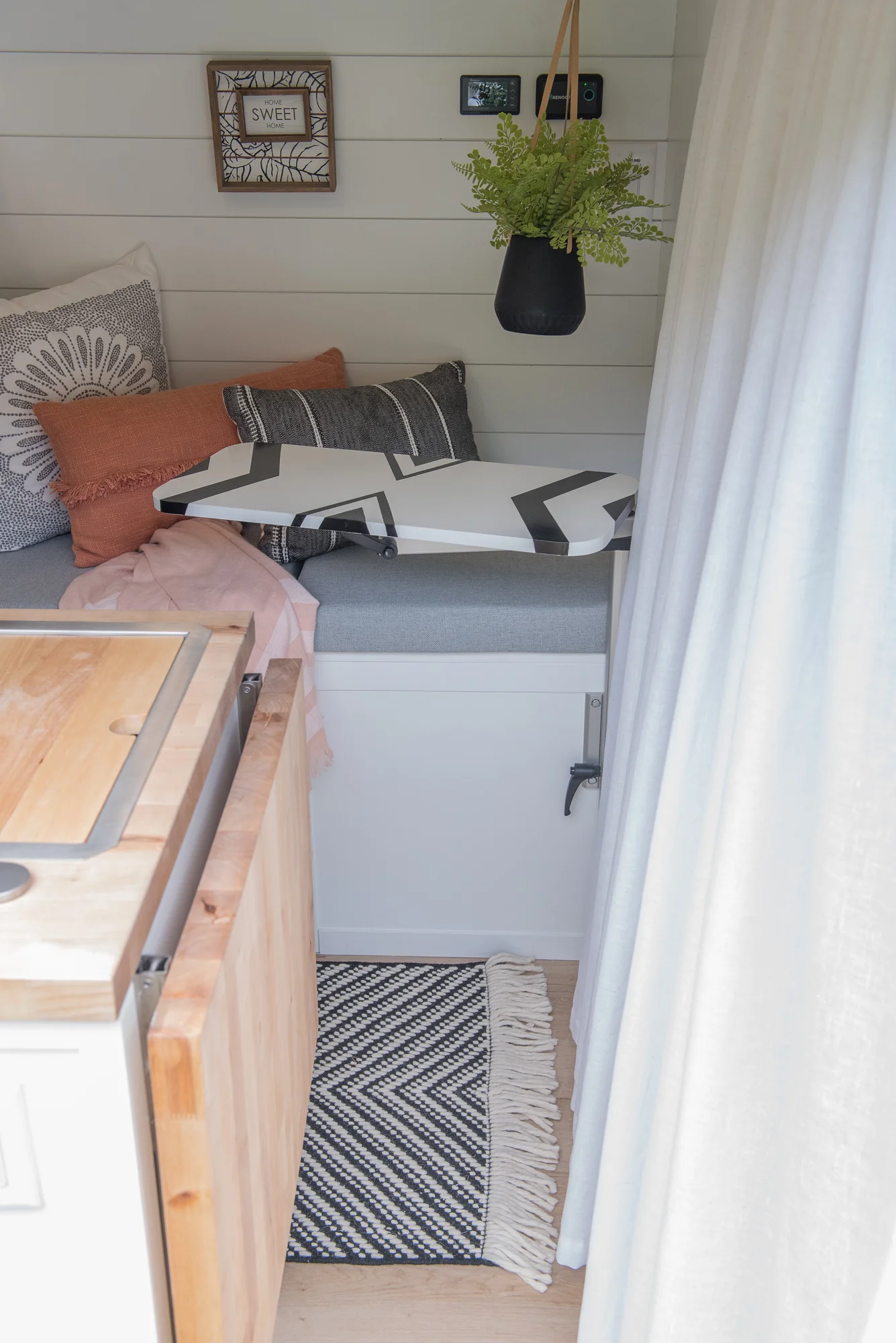 The Drifter 101 custom Ram ProMaster campervan built for Marcia by Drifter Vans, with white shiplap walls, wood countertop, an enclosed shower, and a remote work setup