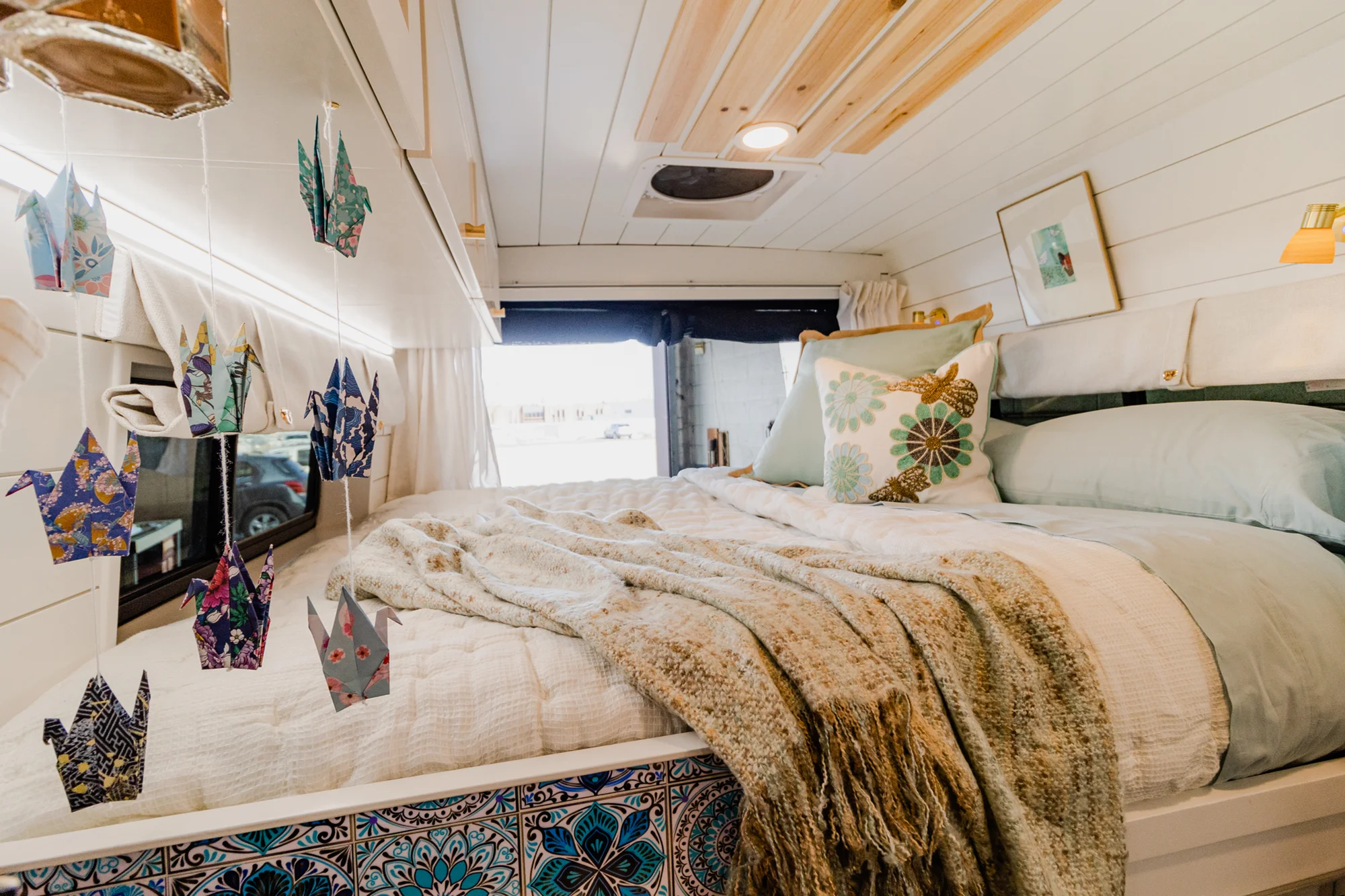 The Drifter 101 custom Ram ProMaster campervan built for Rhonda by Drifter Vans, Wanderer layout with a boho interior, Furrion oven, blue patterned tile backsplash, and brass hardware