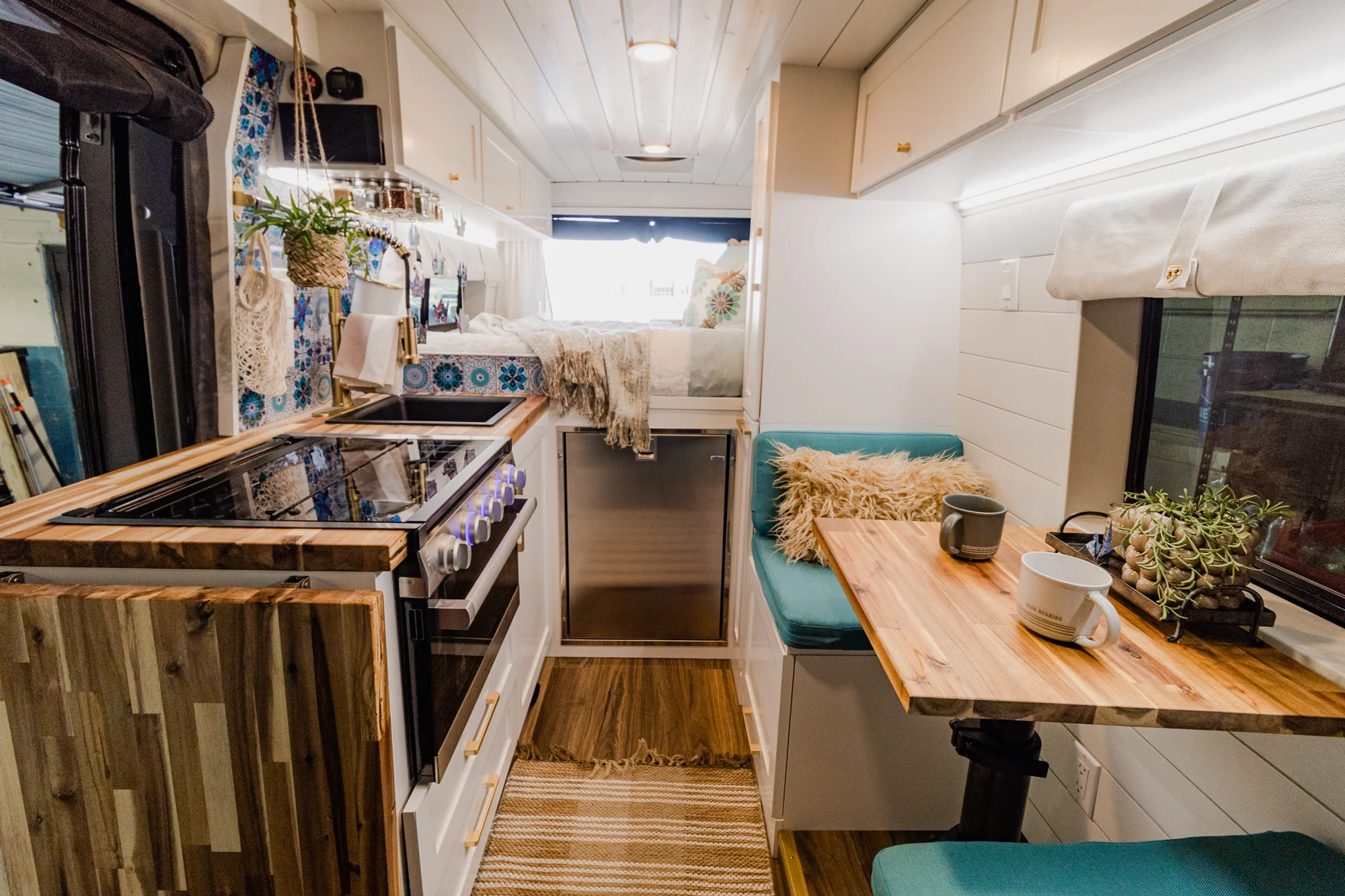 The Drifter 101 custom Ram ProMaster campervan built for Rhonda by Drifter Vans, Wanderer layout with a boho interior, Furrion oven, blue patterned tile backsplash, and brass hardware