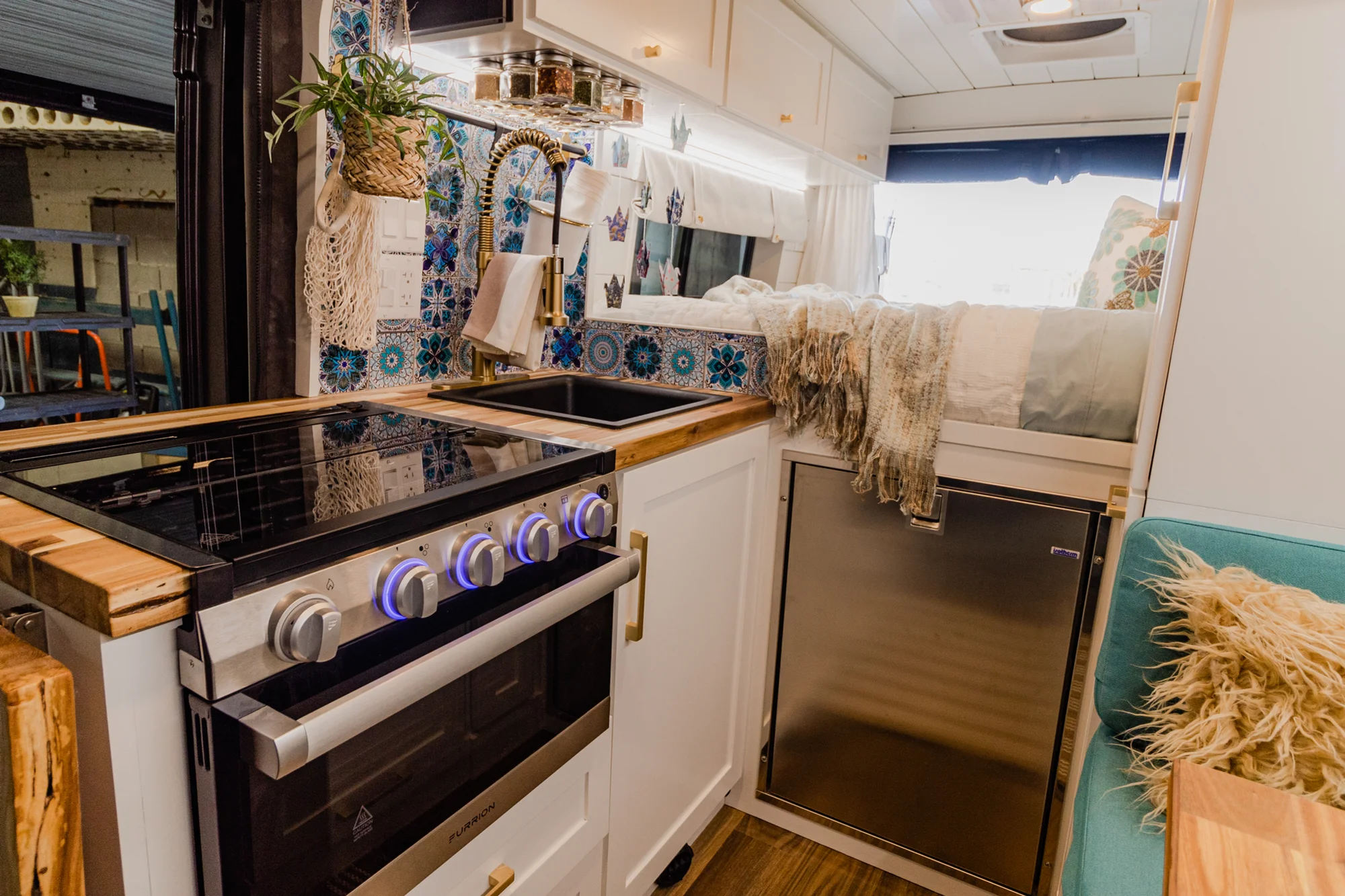 The Drifter 101 custom Ram ProMaster campervan built for Rhonda by Drifter Vans, Wanderer layout with a boho interior, Furrion oven, blue patterned tile backsplash, and brass hardware