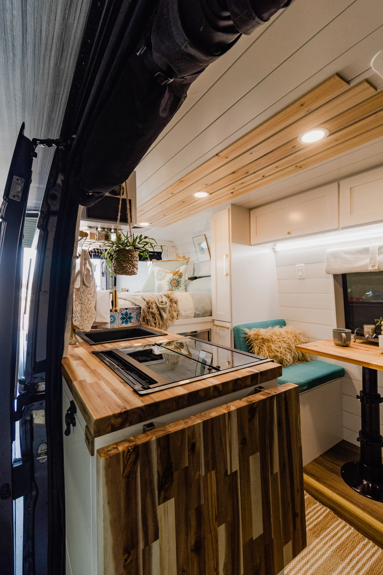 The Drifter 101 custom Ram ProMaster campervan built for Rhonda by Drifter Vans, Wanderer layout with a boho interior, Furrion oven, blue patterned tile backsplash, and brass hardware