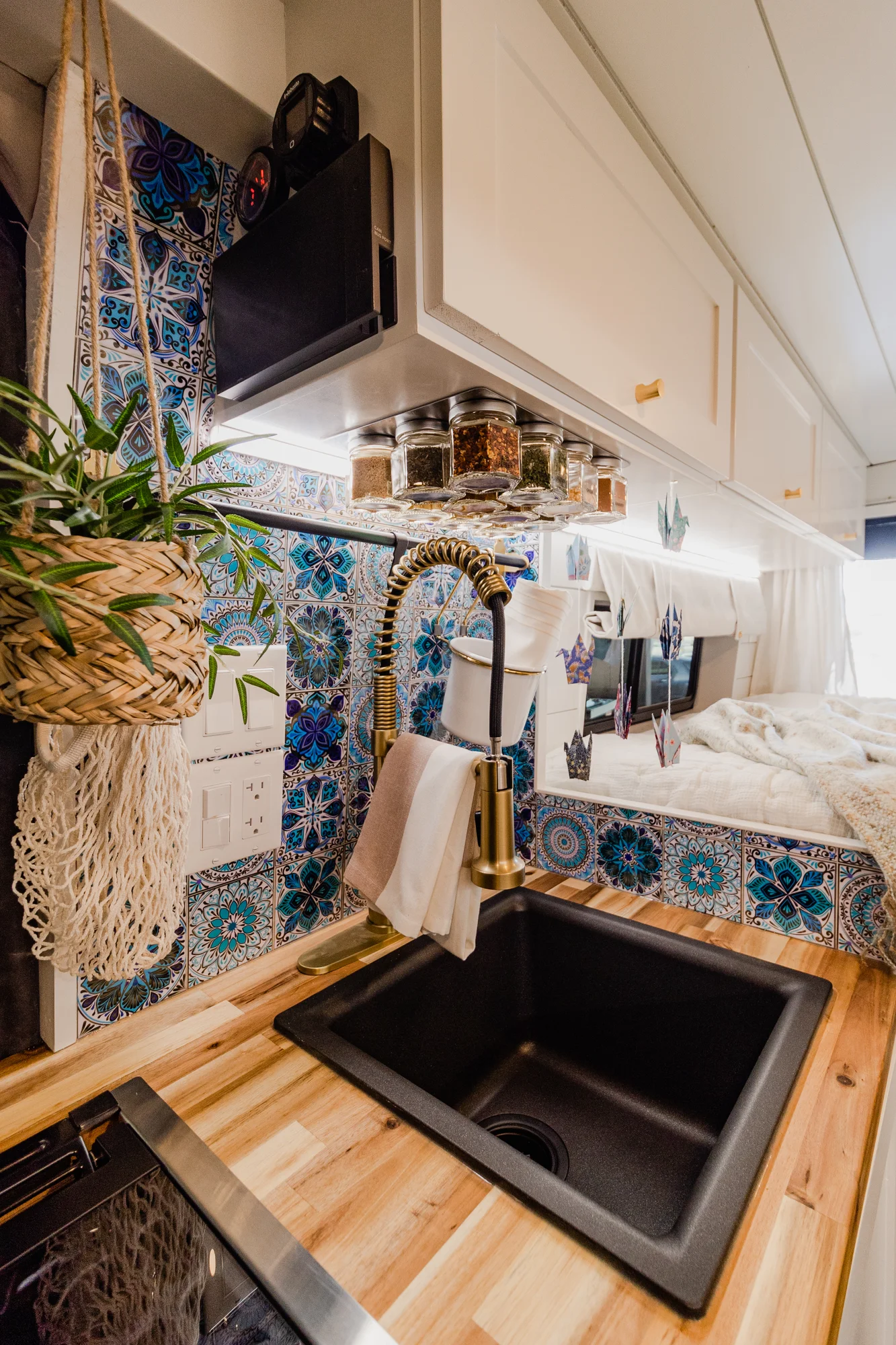 The Drifter 101 custom Ram ProMaster campervan built for Rhonda by Drifter Vans, Wanderer layout with a boho interior, Furrion oven, blue patterned tile backsplash, and brass hardware