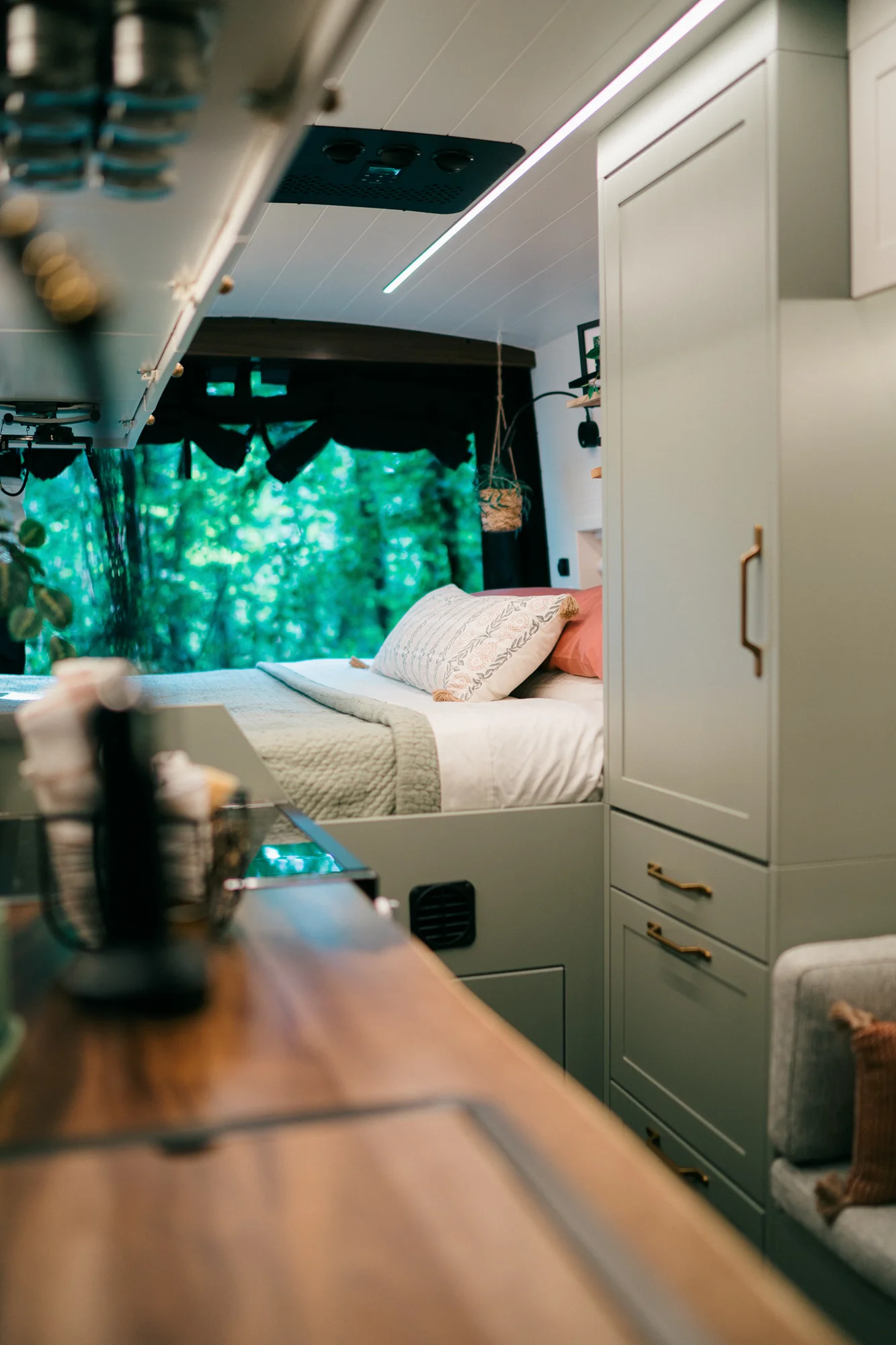 The Drifter 101 custom Ford Transit campervan built for Heather by Drifter Vans, Drifter layout with a full oven, patterned tile backsplash, brass faucet, and natural wood cabinetry