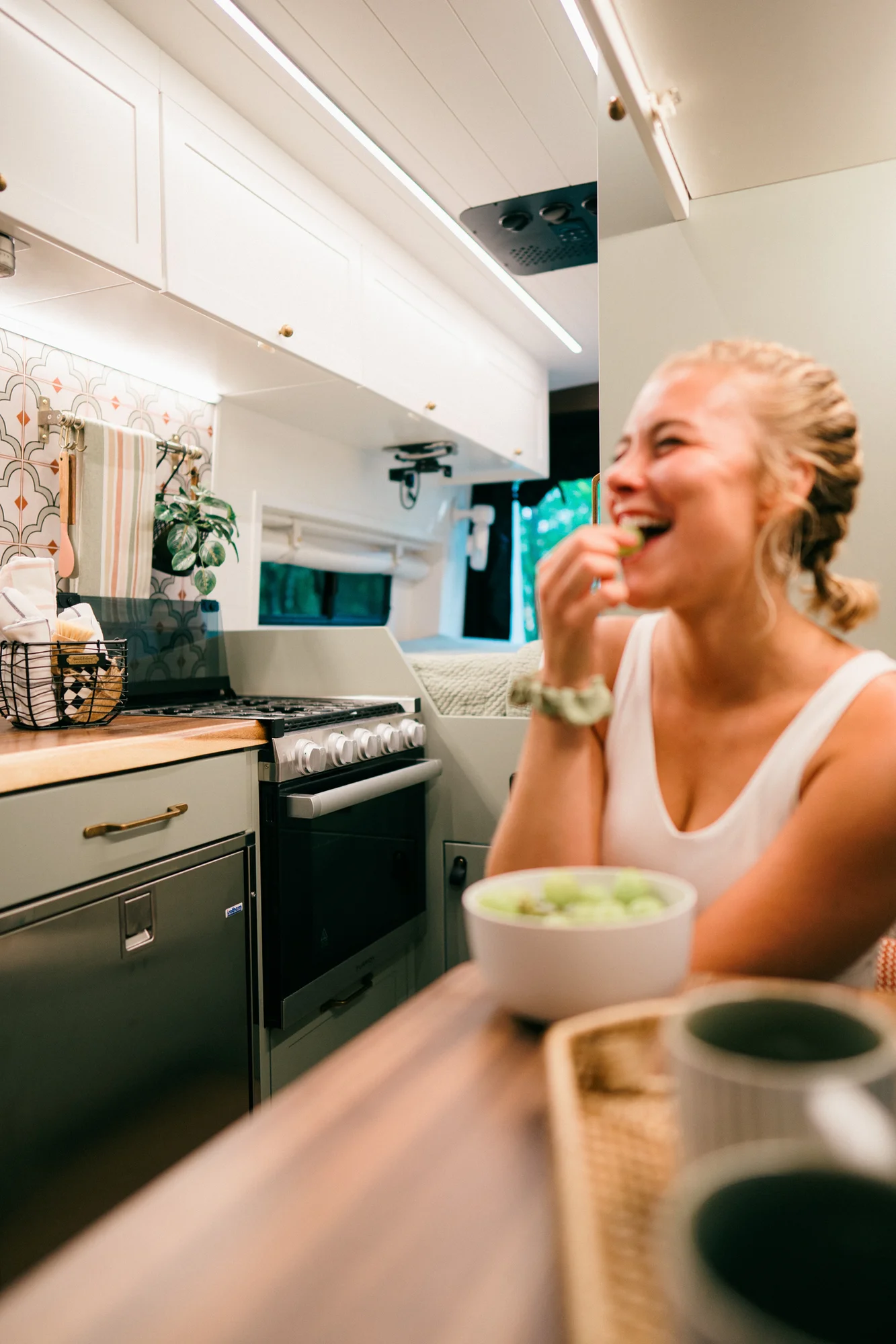 The Drifter 101 custom Ford Transit campervan built for Heather by Drifter Vans, Drifter layout with a full oven, patterned tile backsplash, brass faucet, and natural wood cabinetry