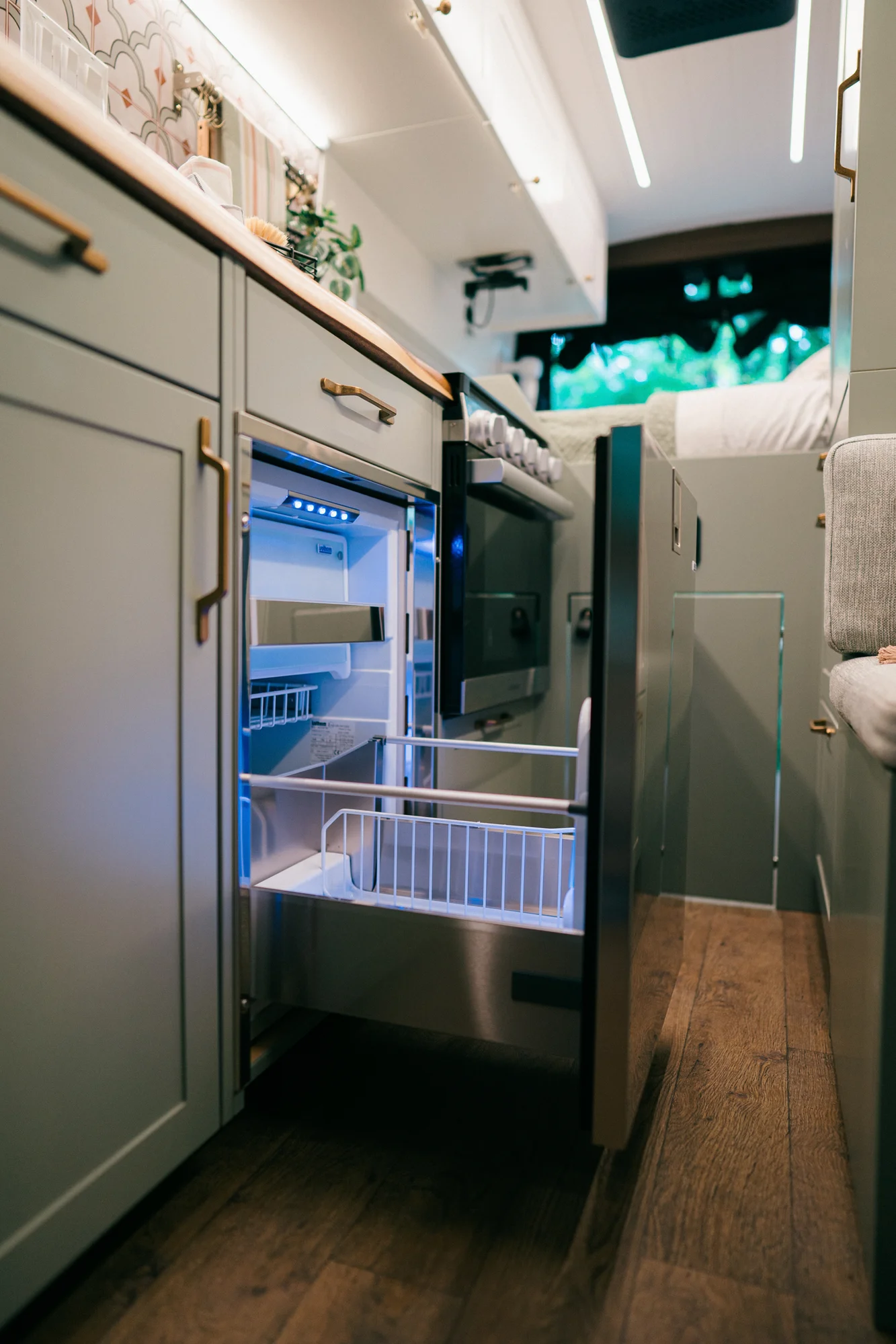 The Drifter 101 custom Ford Transit campervan built for Heather by Drifter Vans, Drifter layout with a full oven, patterned tile backsplash, brass faucet, and natural wood cabinetry