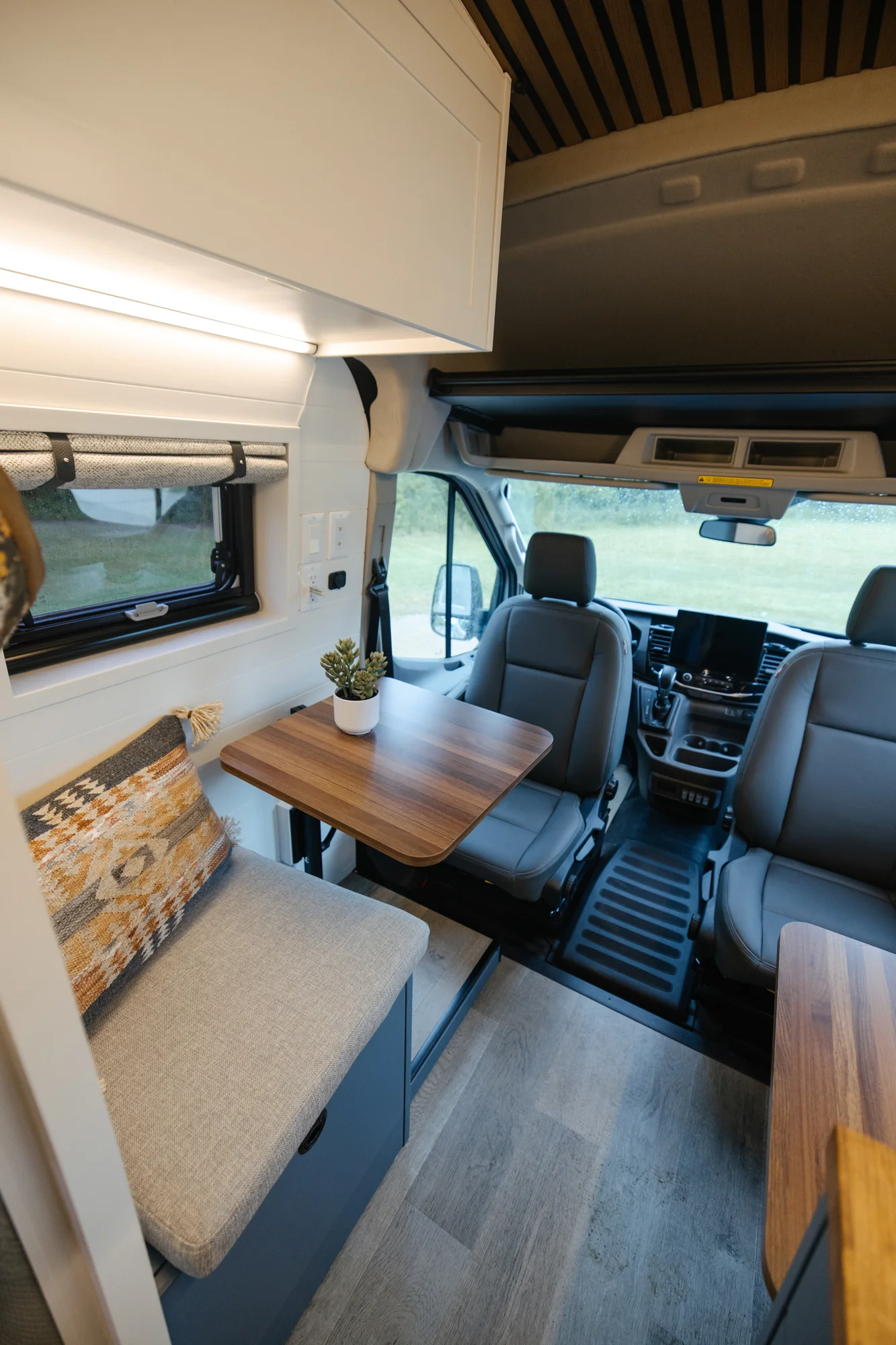 The Drifter 101 custom Ford Transit campervan built for Karen and Jerry by Drifter Vans, Scout layout with navy blue cabinetry, a mountain-engraved backsplash, and butcher block countertop
