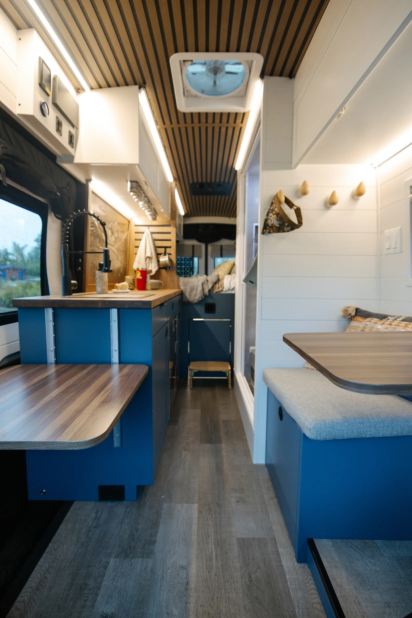 The Drifter 101 custom Ford Transit campervan built for Karen and Jerry by Drifter Vans, Scout layout with navy blue cabinetry, a mountain-engraved backsplash, and butcher block countertop