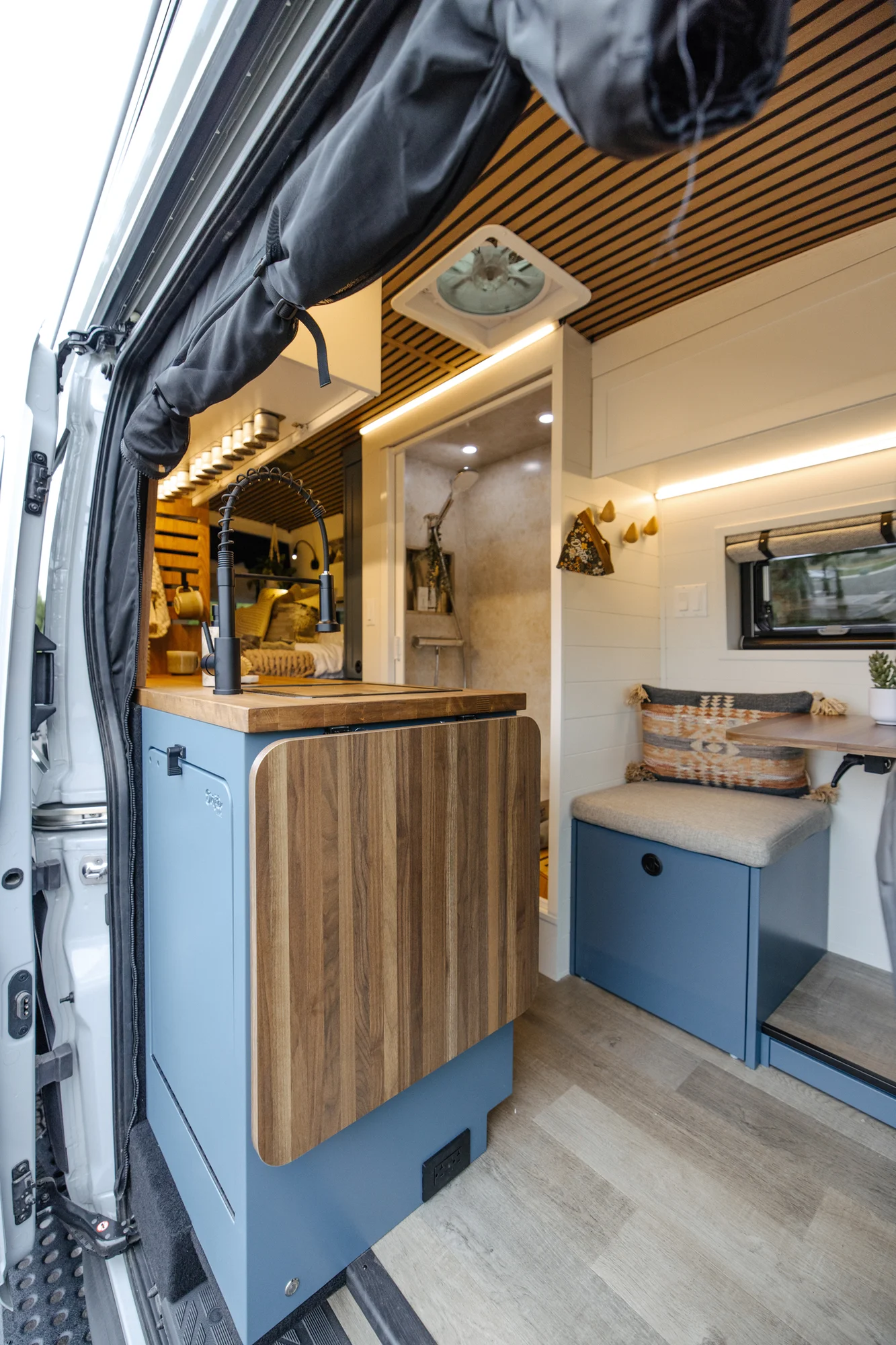 The Drifter 101 custom Ford Transit campervan built for Karen and Jerry by Drifter Vans, Scout layout with navy blue cabinetry, a mountain-engraved backsplash, and butcher block countertop