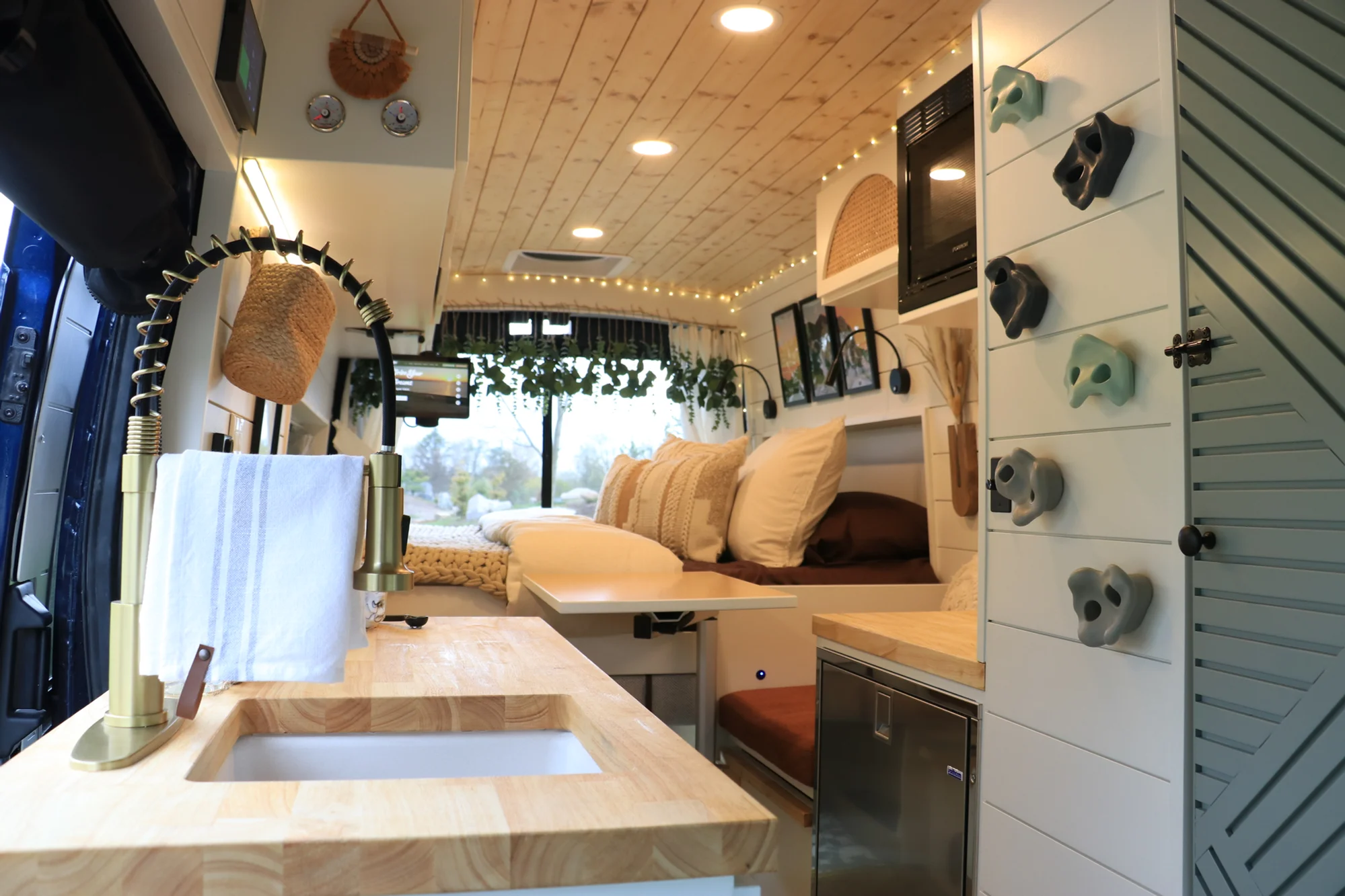 The Drifter 101 custom Ford Transit campervan built for Sarah by Drifter Vans, Nomadik layout with a marble-style wet bath, gold faucet, trifold privacy door, and boho accents