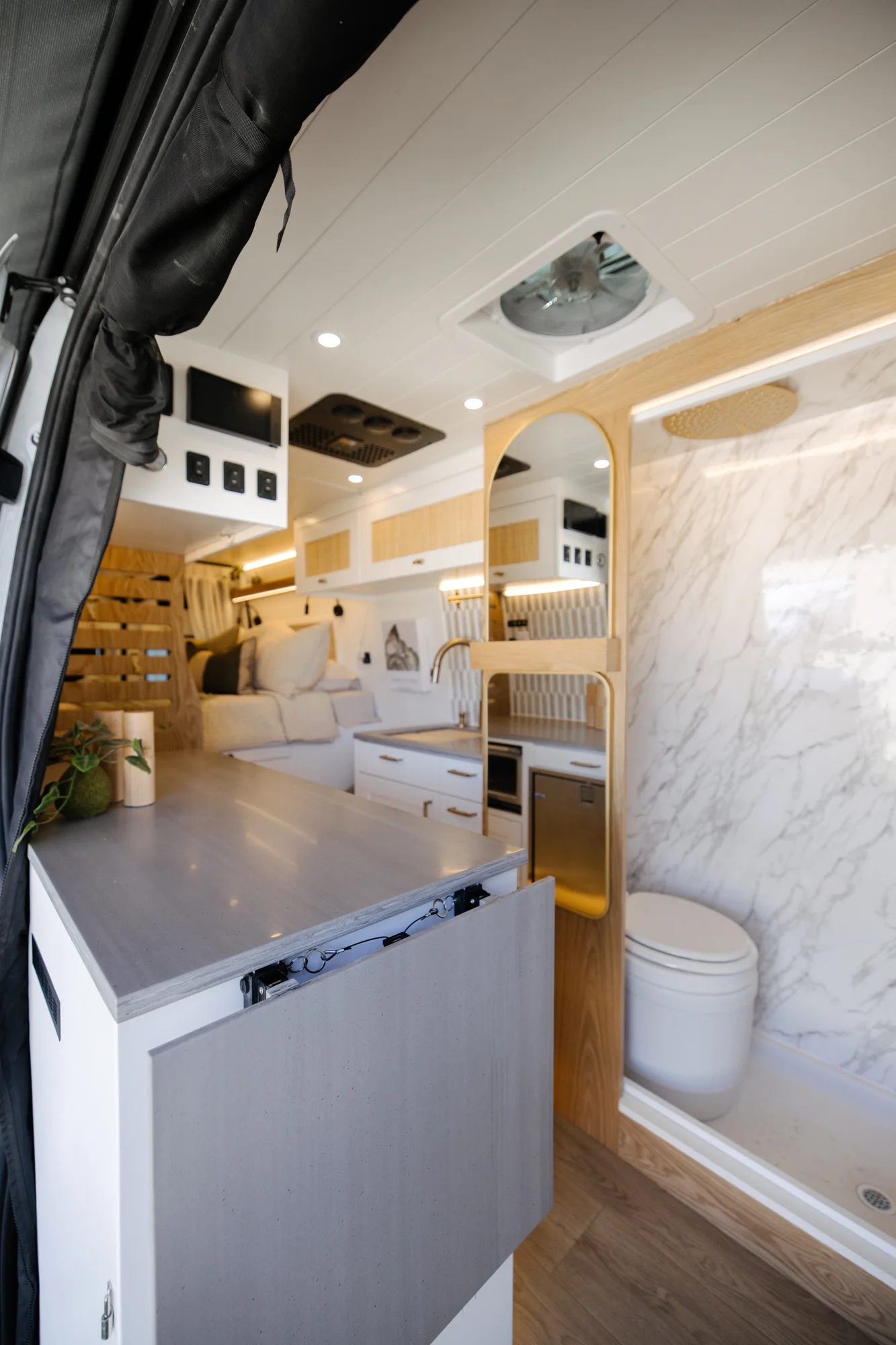 The Drifter 101 custom Ford Transit campervan built for Alison by Drifter Vans, Nomadik layout with a Japandi interior, white cabinetry, gold rain shower, and marble wet bath