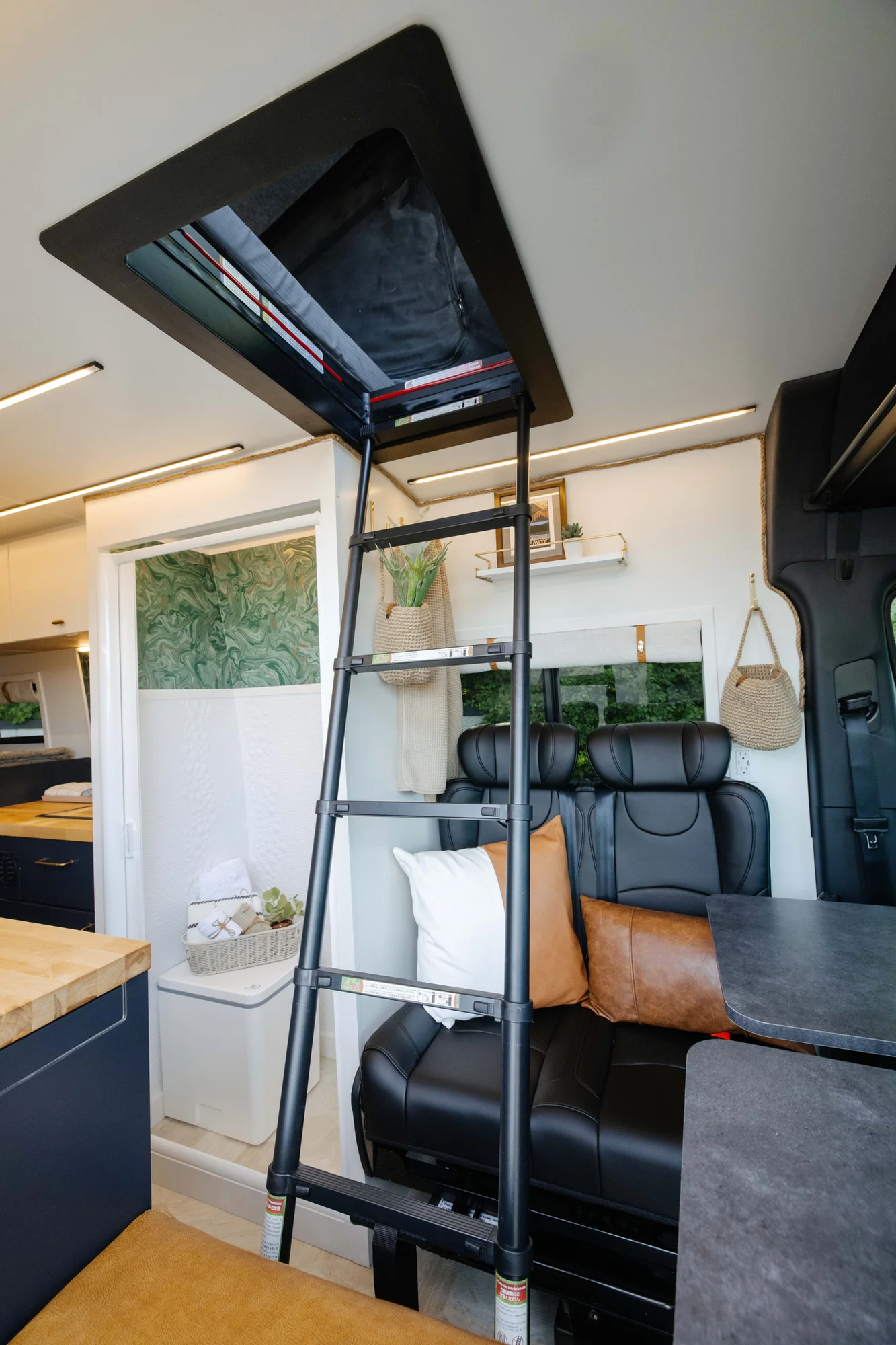 The Drifter 101 custom Mercedes-Benz Sprinter campervan built for Amber by Drifter Vans, with a pop-top sleeping area, navy cabinetry, butcher block counters, and gold hardware