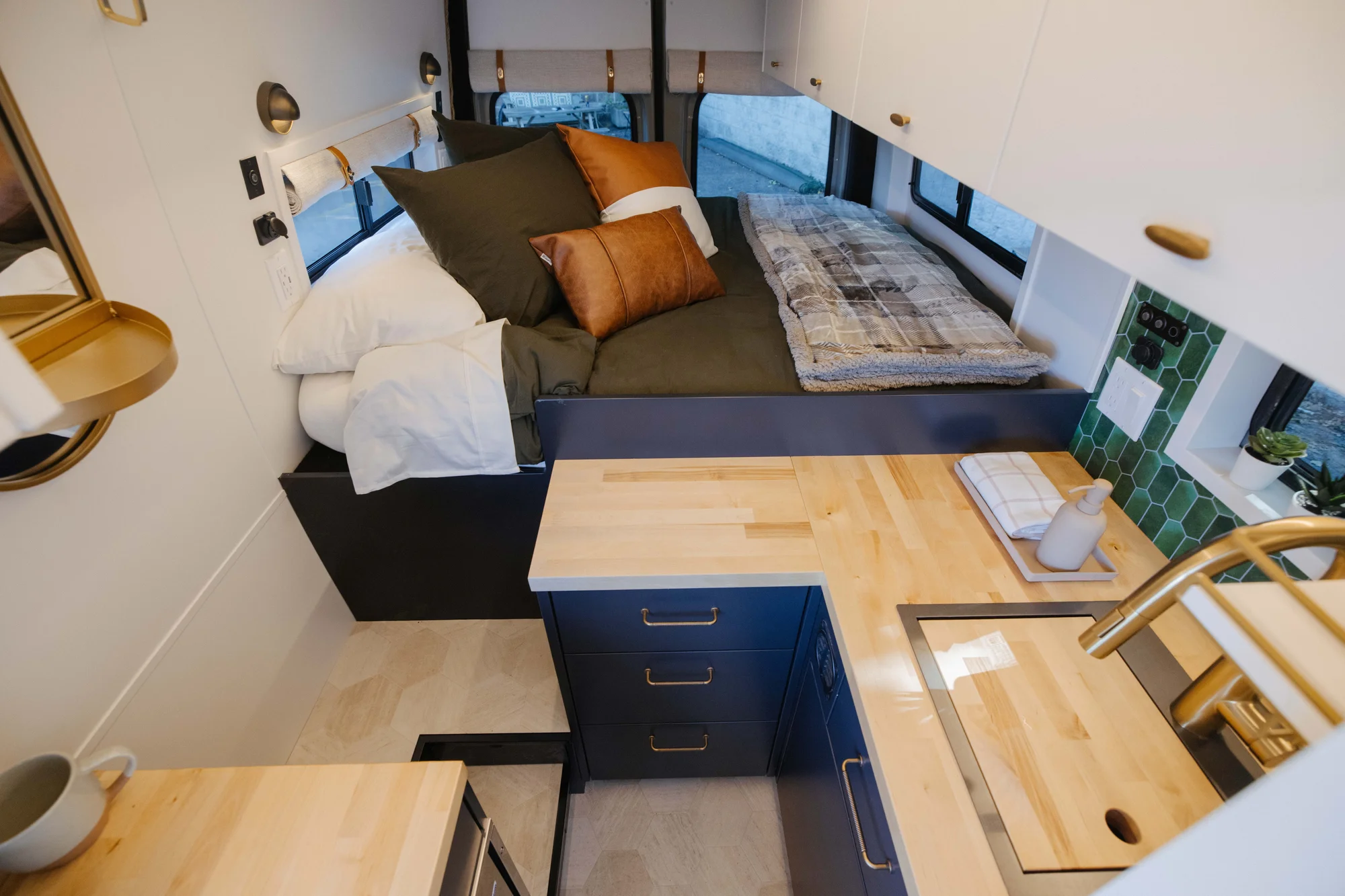 The Drifter 101 custom Mercedes-Benz Sprinter campervan built for Amber by Drifter Vans, with a pop-top sleeping area, navy cabinetry, butcher block counters, and gold hardware