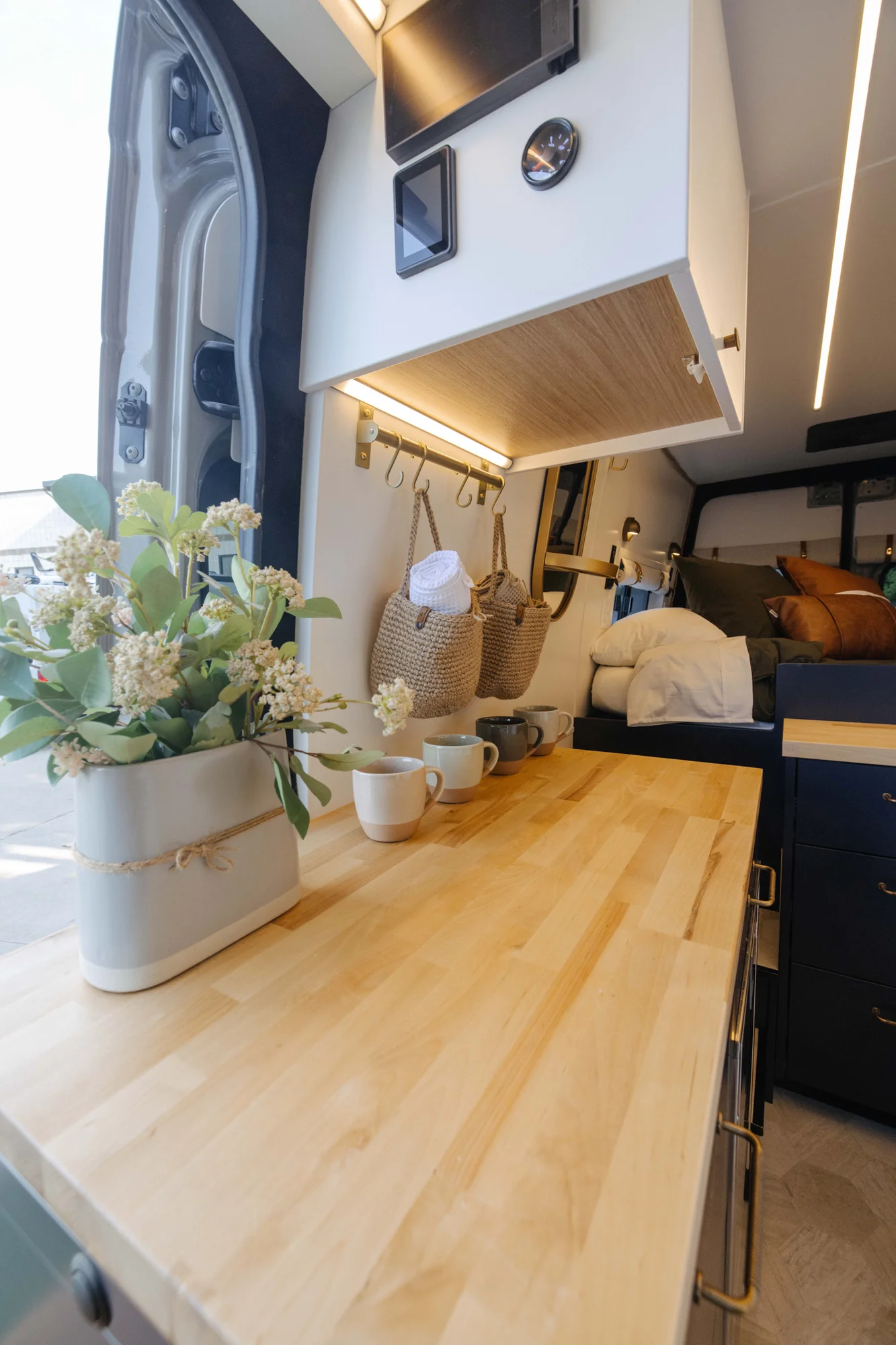 The Drifter 101 custom Mercedes-Benz Sprinter campervan built for Amber by Drifter Vans, with a pop-top sleeping area, navy cabinetry, butcher block counters, and gold hardware
