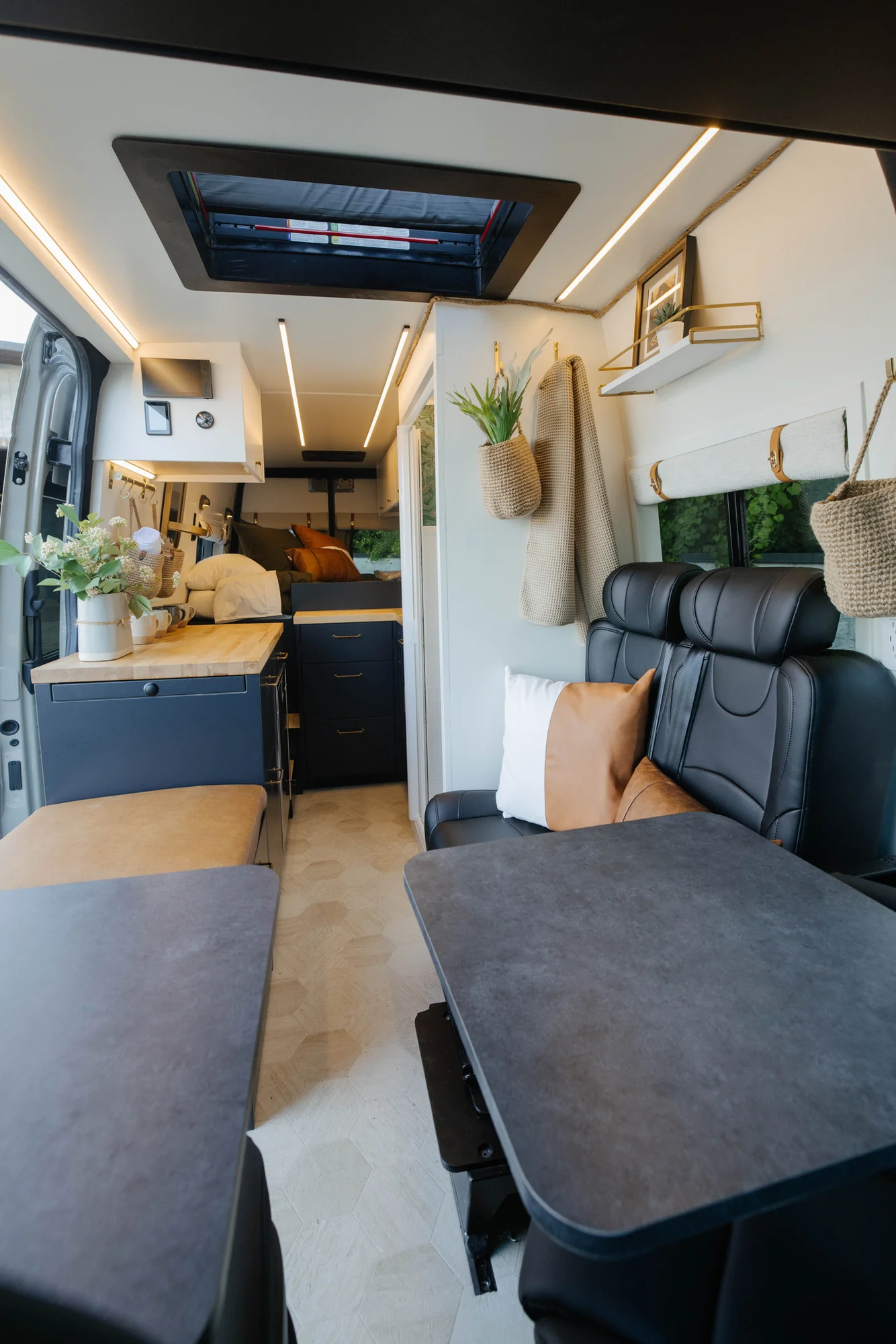 The Drifter 101 custom Mercedes-Benz Sprinter campervan built for Amber by Drifter Vans, with a pop-top sleeping area, navy cabinetry, butcher block counters, and gold hardware