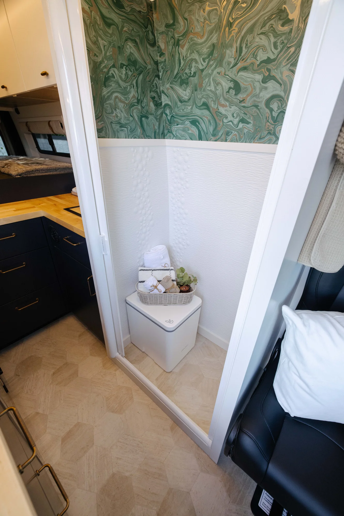 The Drifter 101 custom Mercedes-Benz Sprinter campervan built for Amber by Drifter Vans, with a pop-top sleeping area, navy cabinetry, butcher block counters, and gold hardware