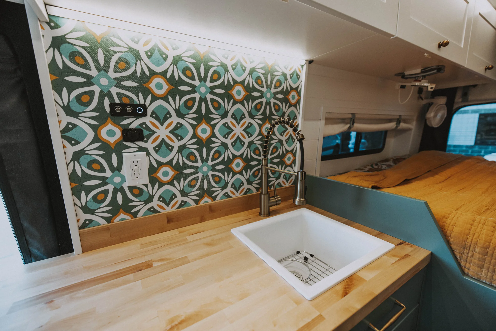 The Drifter 101 custom Ford Transit campervan built for Kristina by Drifter Vans, Drifter layout with a Moroccan-inspired blue tile backsplash, warm wood cabinetry, and a built-in dog nook