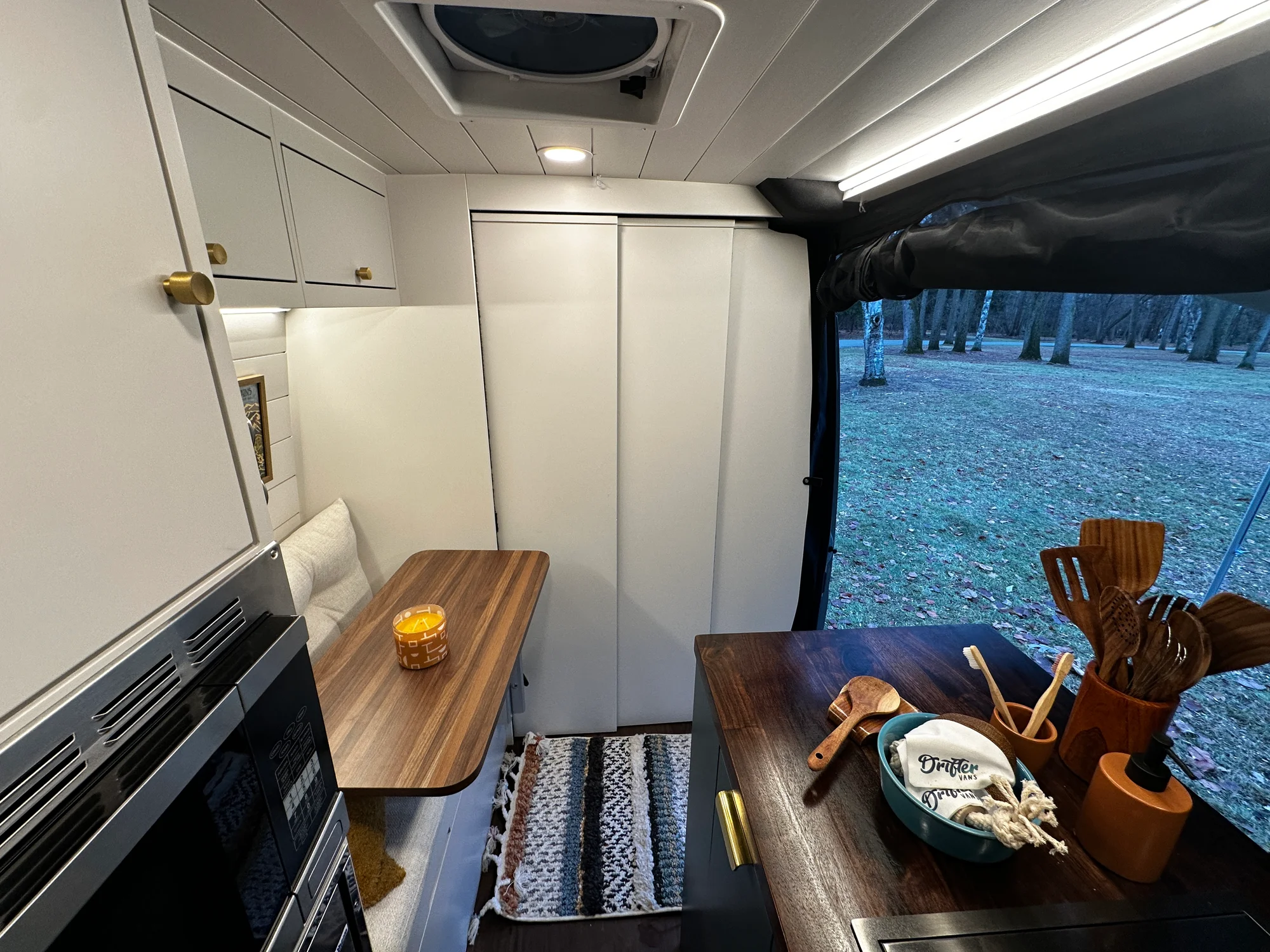 The Drifter 101 custom Ford Transit campervan built for Lynne by Drifter Vans, Drifter layout with a mid-century modern interior, dark walnut countertop, and gold hardware