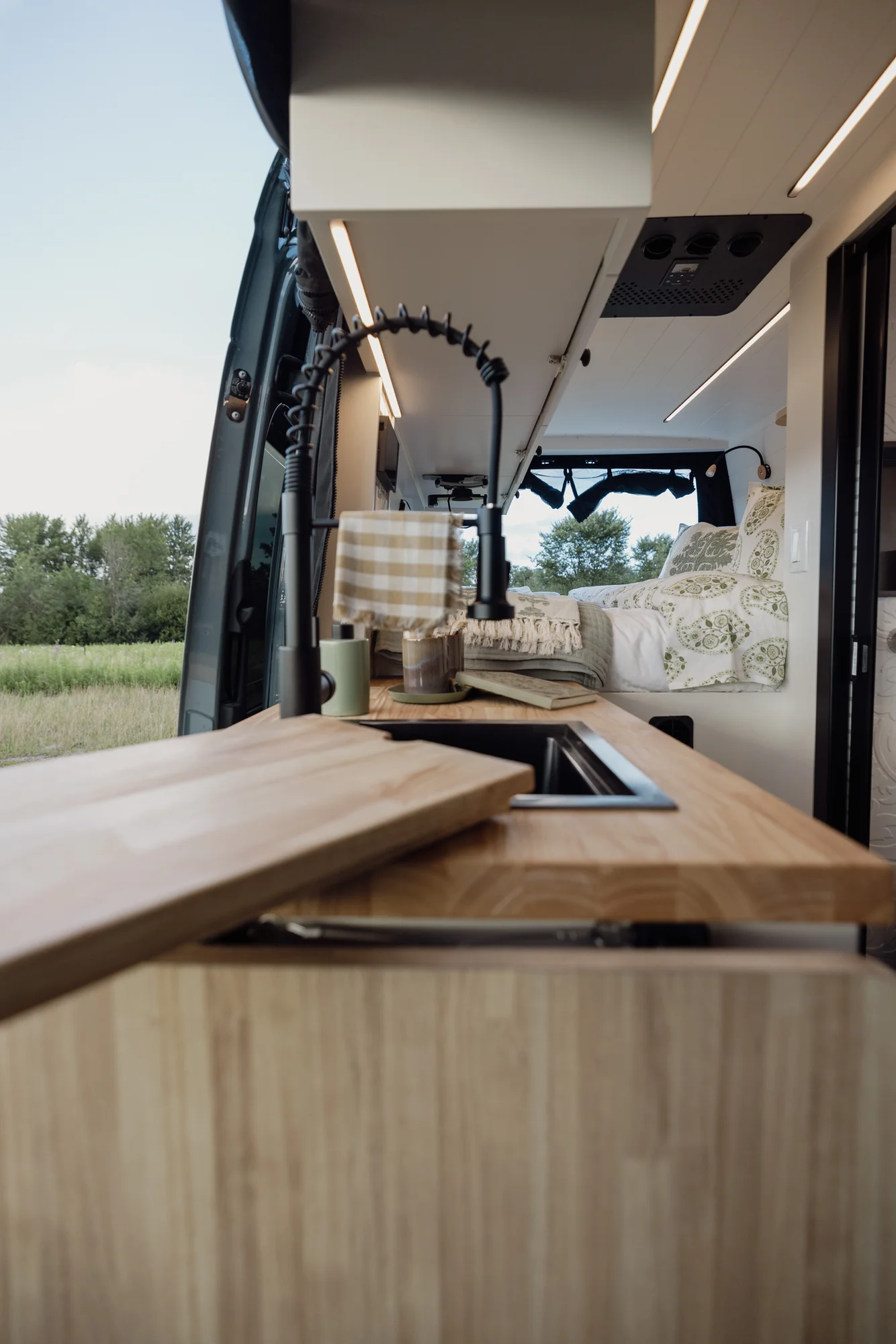 The Drifter 101 custom Mercedes-Benz Sprinter campervan built for Tanya by Drifter Vans, rustic interior with light blue cabinetry, butcher block countertop, and oil-rubbed bronze fixtures