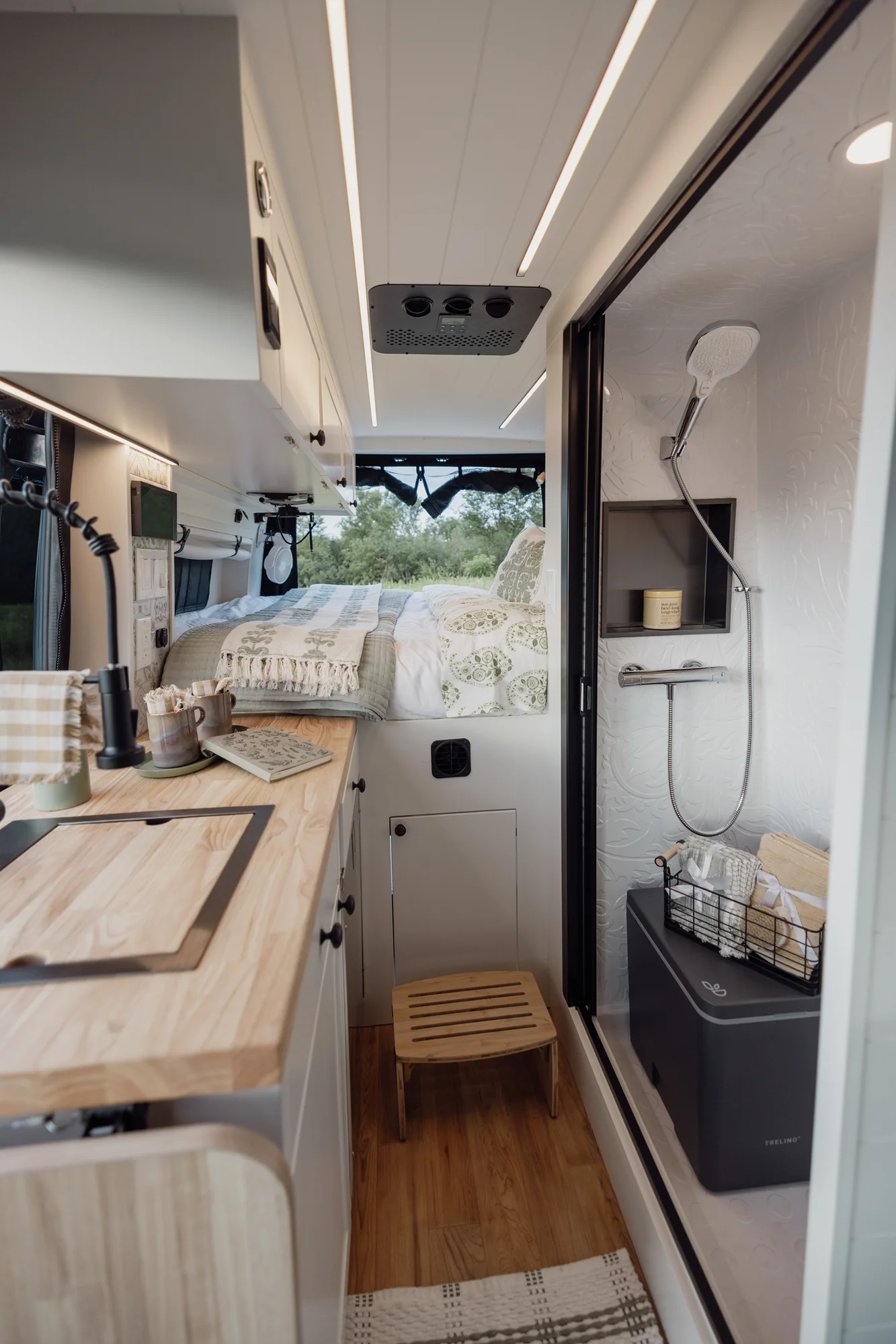 The Drifter 101 custom Mercedes-Benz Sprinter campervan built for Tanya by Drifter Vans, rustic interior with light blue cabinetry, butcher block countertop, and oil-rubbed bronze fixtures