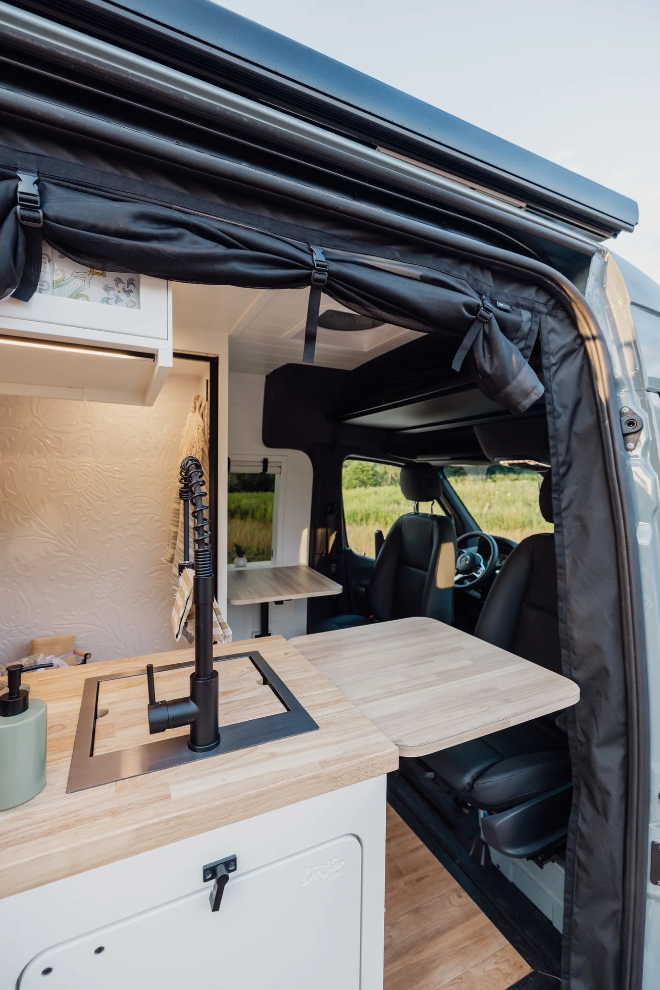 The Drifter 101 custom Mercedes-Benz Sprinter campervan built for Tanya by Drifter Vans, rustic interior with light blue cabinetry, butcher block countertop, and oil-rubbed bronze fixtures