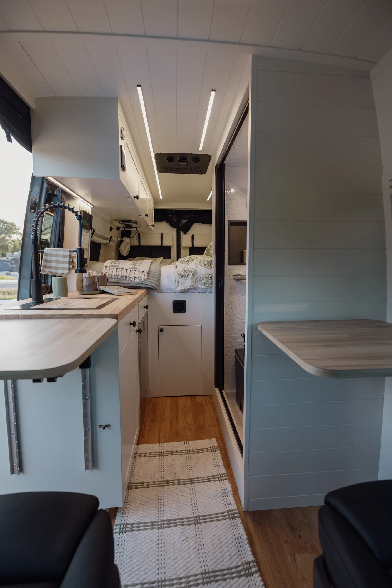 The Drifter 101 custom Mercedes-Benz Sprinter campervan built for Tanya by Drifter Vans, rustic interior with light blue cabinetry, butcher block countertop, and oil-rubbed bronze fixtures