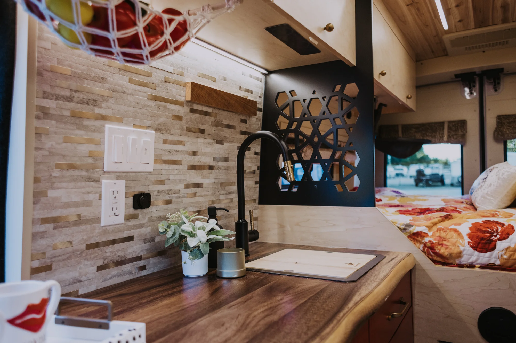 The Drifter 101 custom Ford Transit campervan built for Kim by Drifter Vans, Drifter layout with floral bedding, wood ceiling, and black shower fixtures