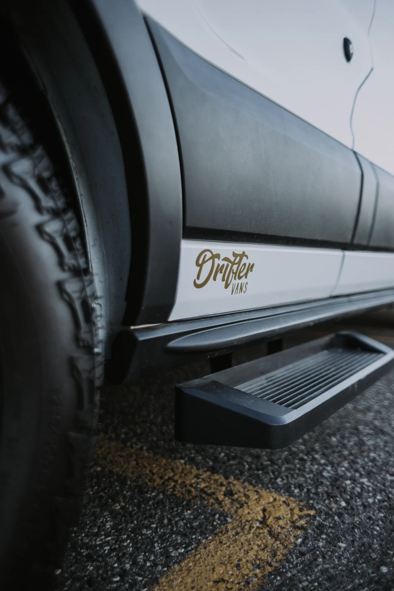 The Drifter 101 custom Ford Transit campervan built for Kim by Drifter Vans, Drifter layout with floral bedding, wood ceiling, and black shower fixtures
