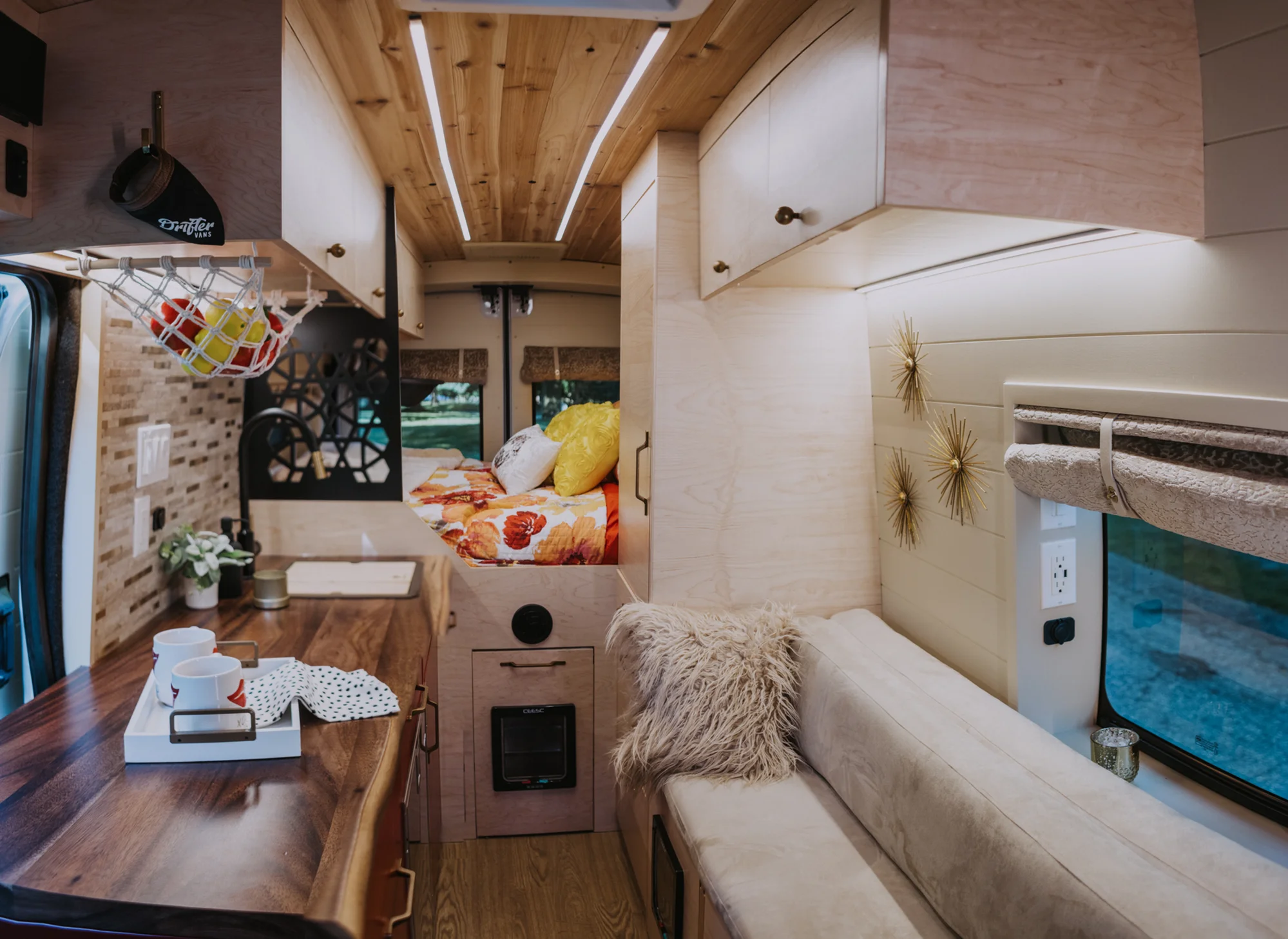 The Drifter 101 custom Ford Transit campervan built for Kim by Drifter Vans, Drifter layout with floral bedding, wood ceiling, and black shower fixtures