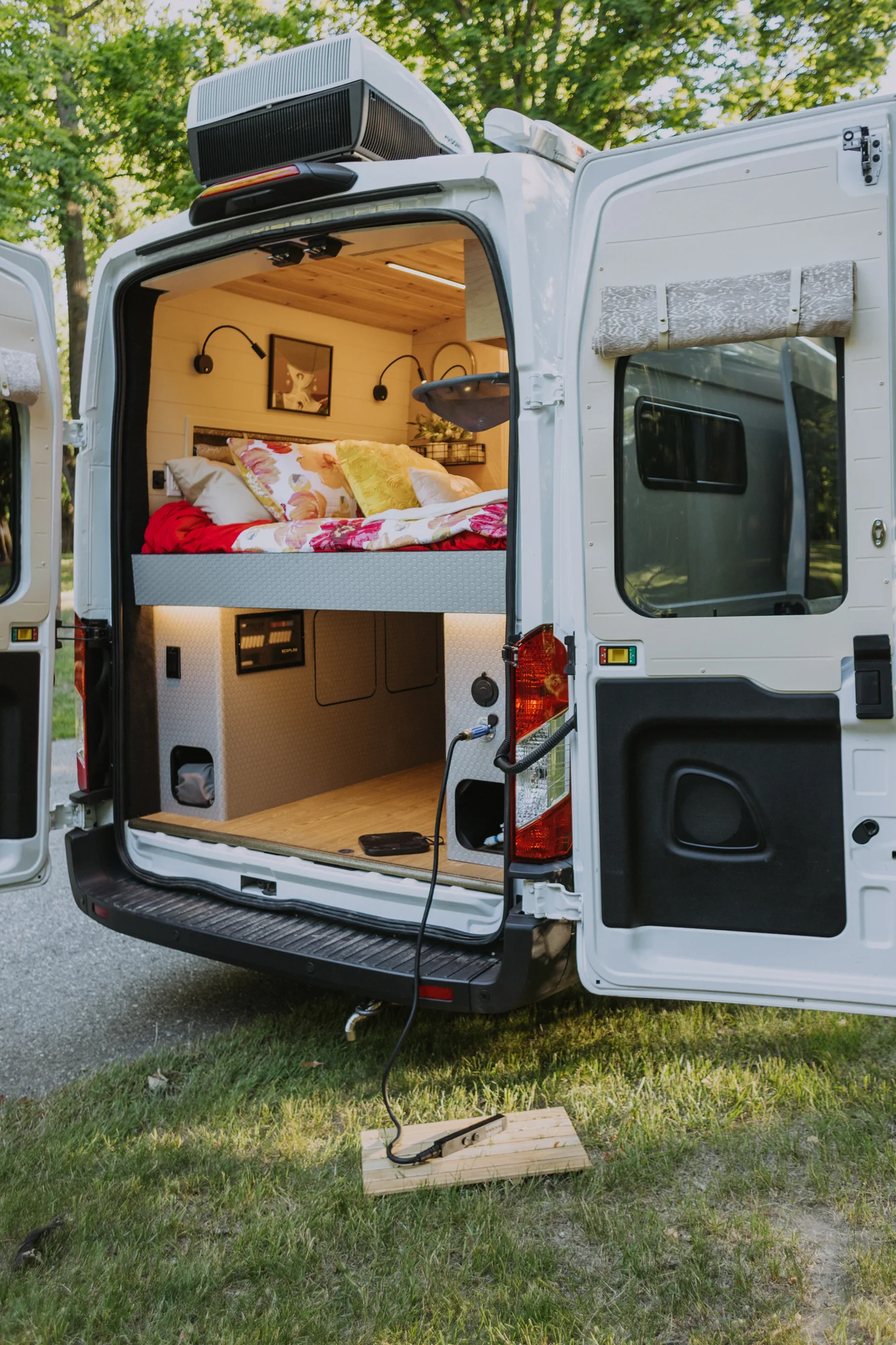 The Drifter 101 custom Ford Transit campervan built for Kim by Drifter Vans, Drifter layout with floral bedding, wood ceiling, and black shower fixtures